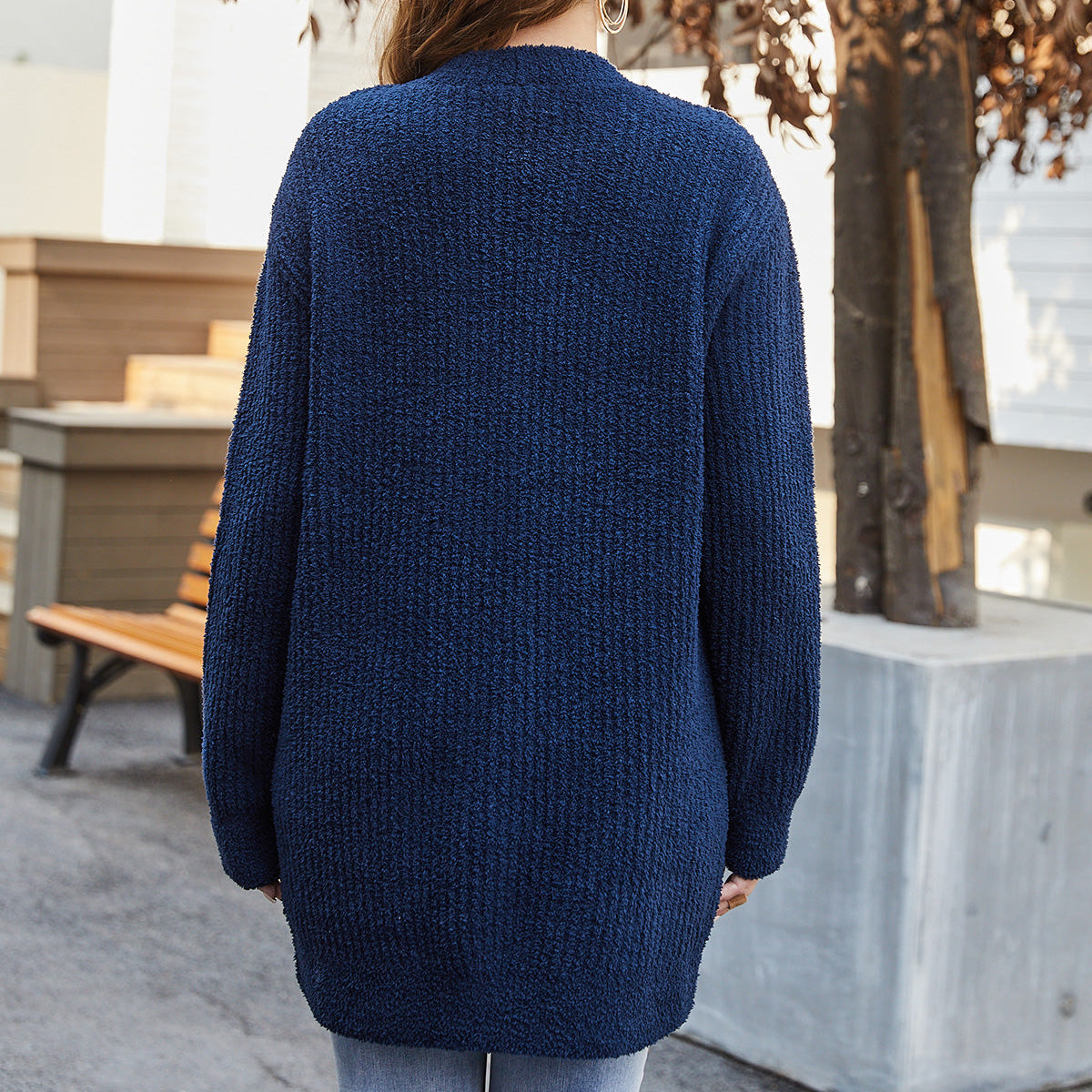 Person wearing a blue cardigan standing outdoors with trees and a bench in the background #color_Navy Blue