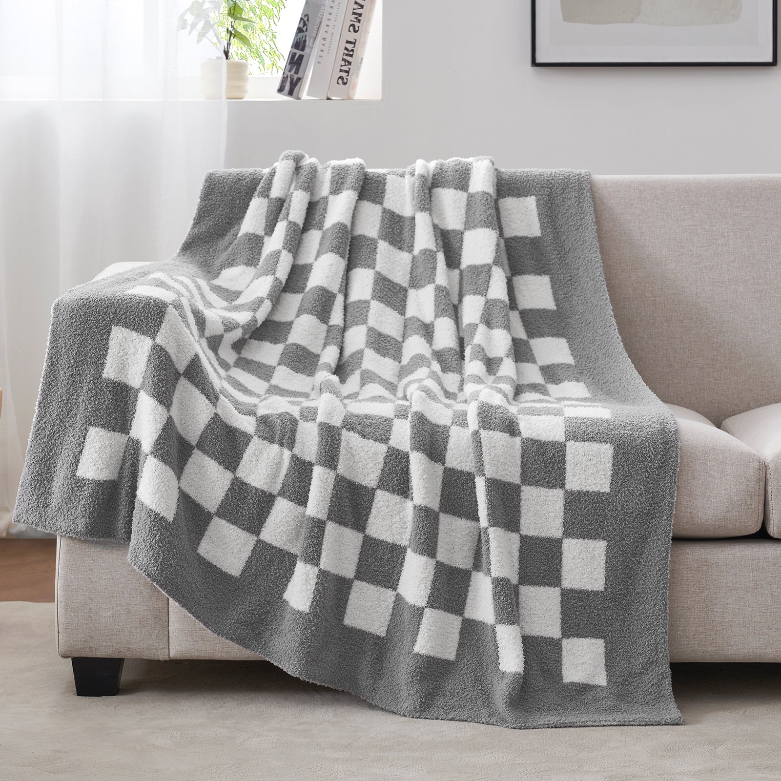 Gray and white checkered blanket draped over a sofa in a living room setting. #color_Checkered Grey