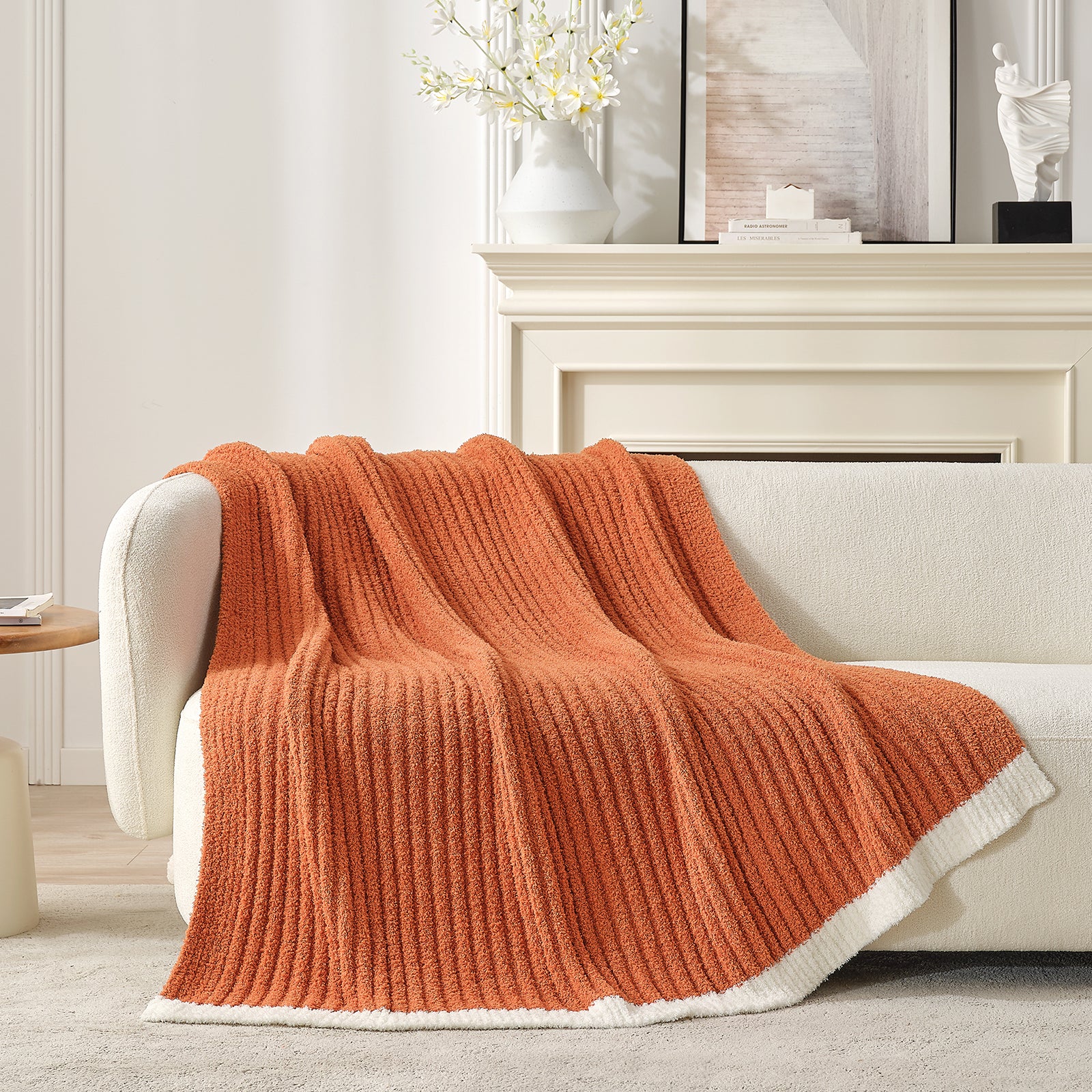 Orange knitted blanket draped over a white sofa in a living room setting. #color_Burnt Orange