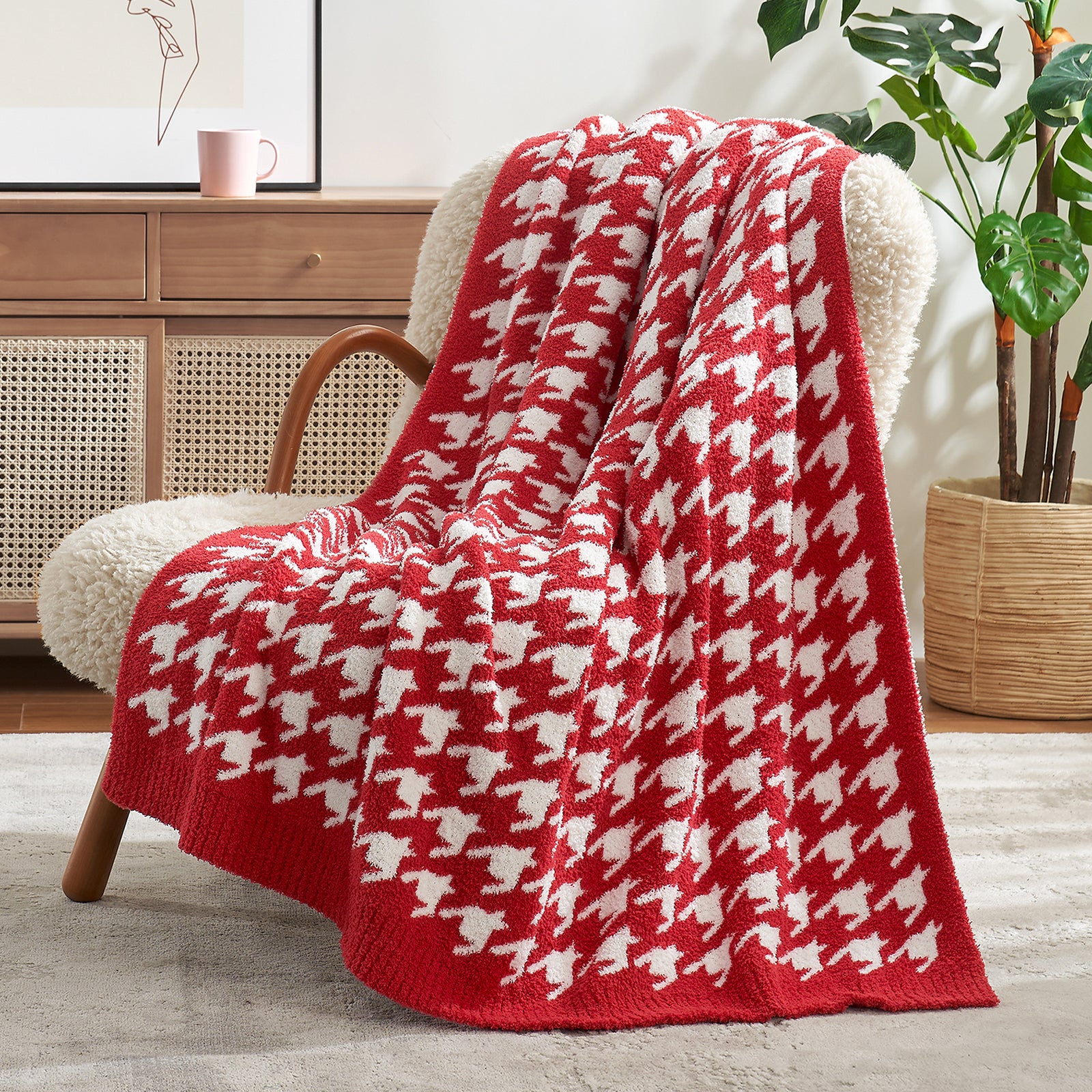 Red and white patterned blanket draped over a chair in a room with a plant and wooden cabinet. #color_Red