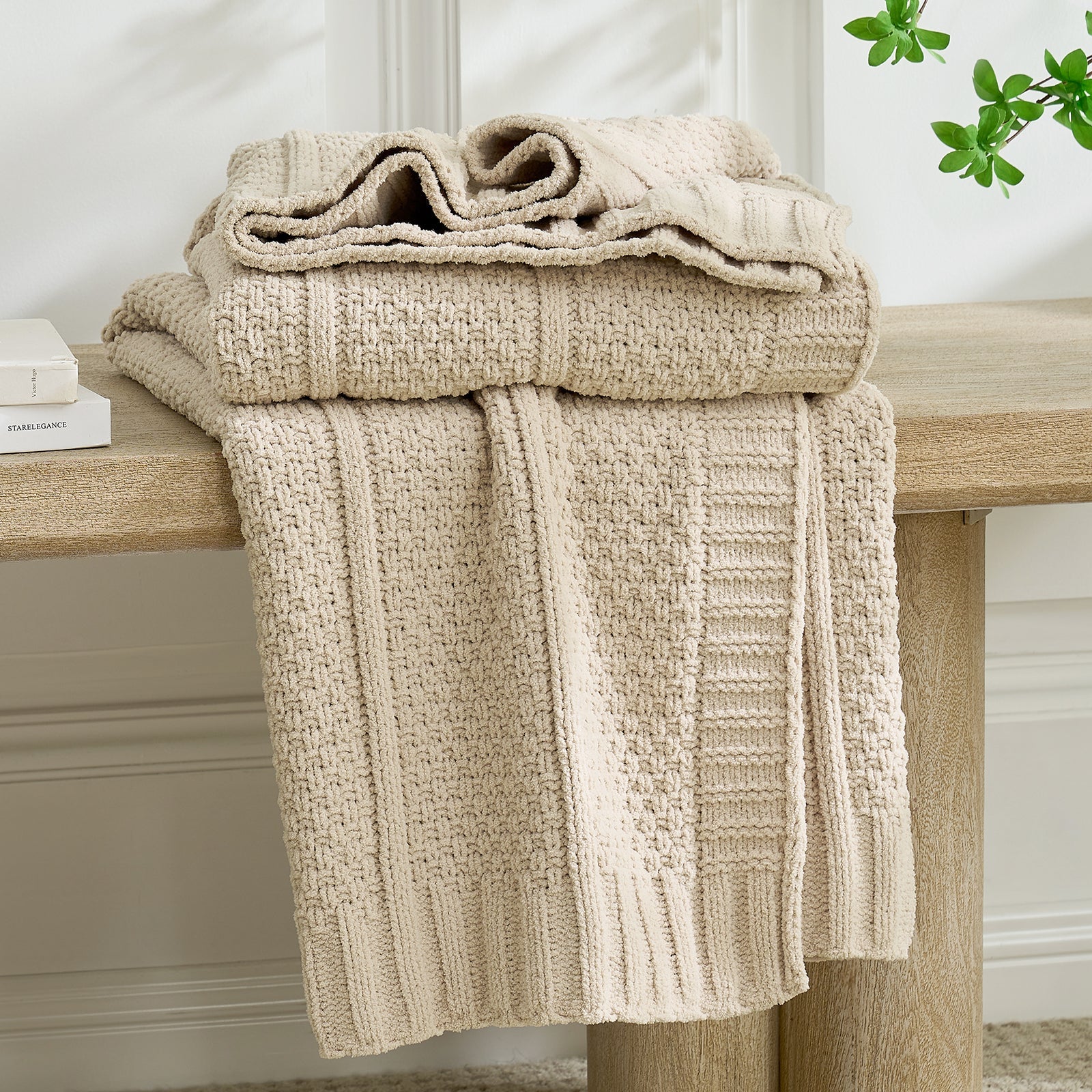 Beige knitted blanket draped over a wooden surface with a neutral background #color_Beige