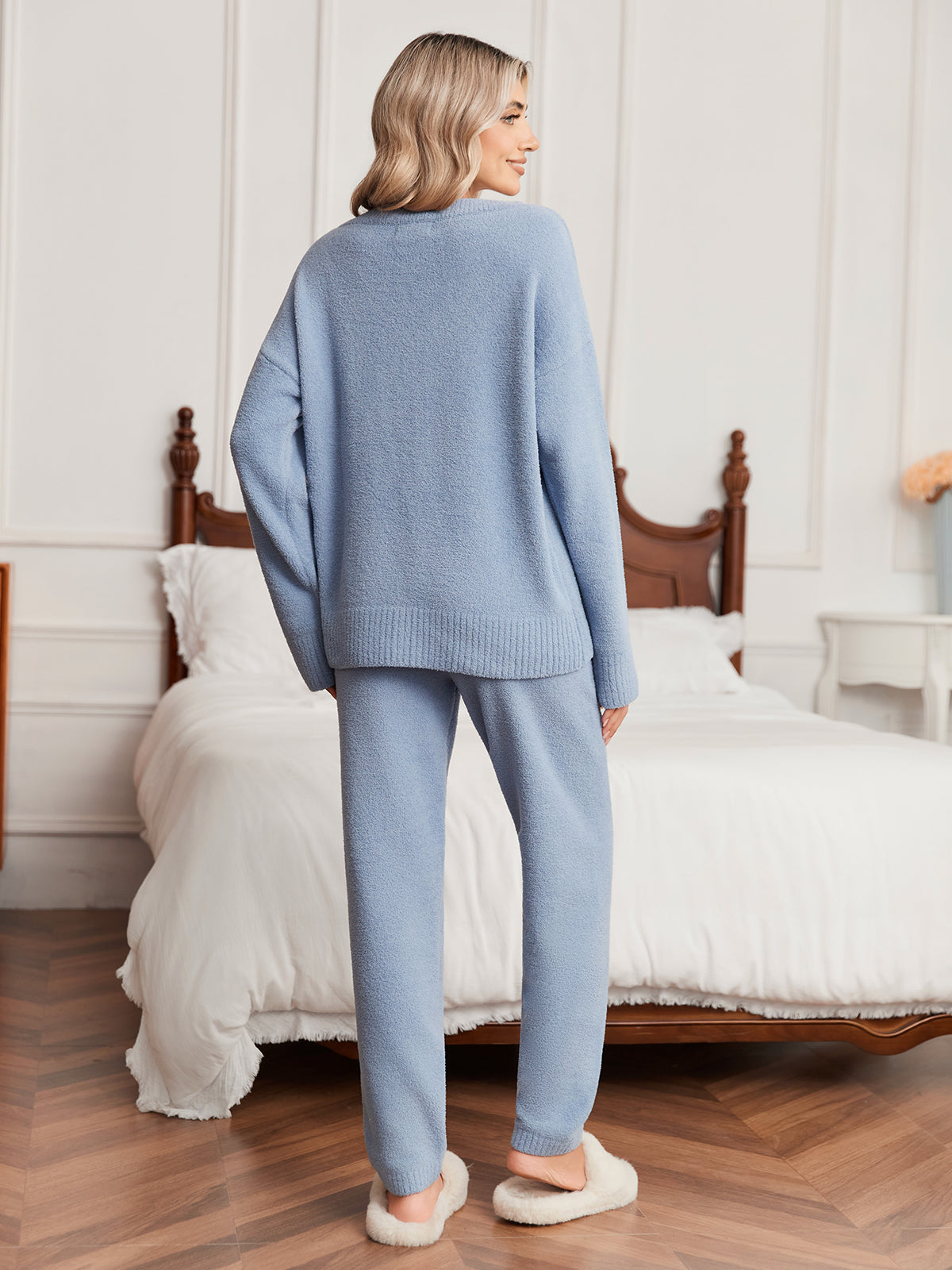 Woman wearing a light blue sweater and pants in a bedroom setting. #color_Blue