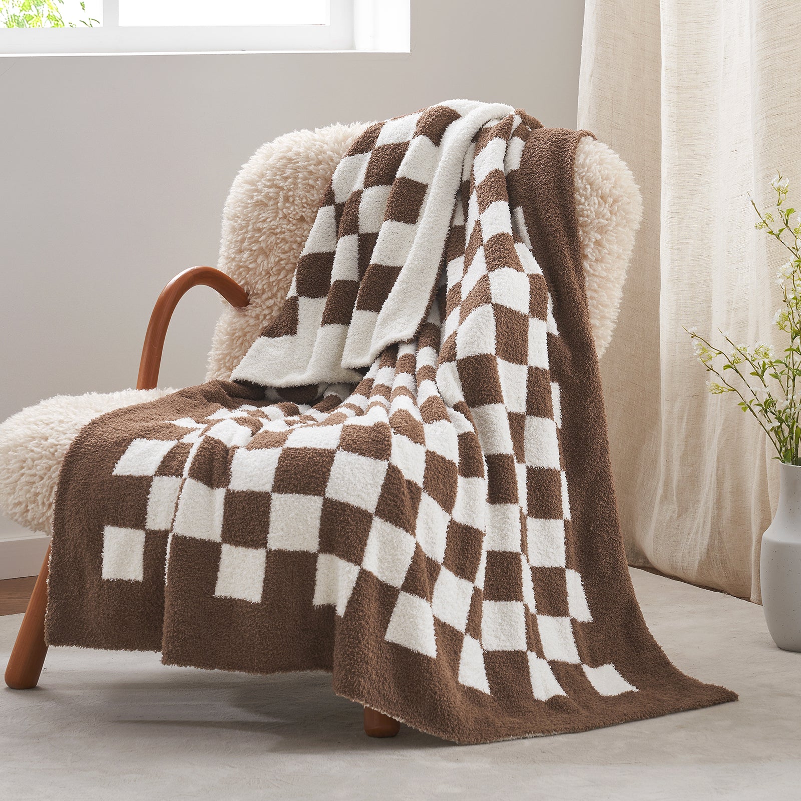 Checkered brown and white blanket draped over a chair in a cozy room.#color_Checkered Brown