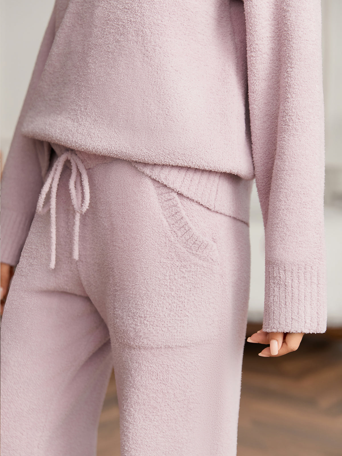 Person wearing a pink knit outfit with a blurred background #color_Purple