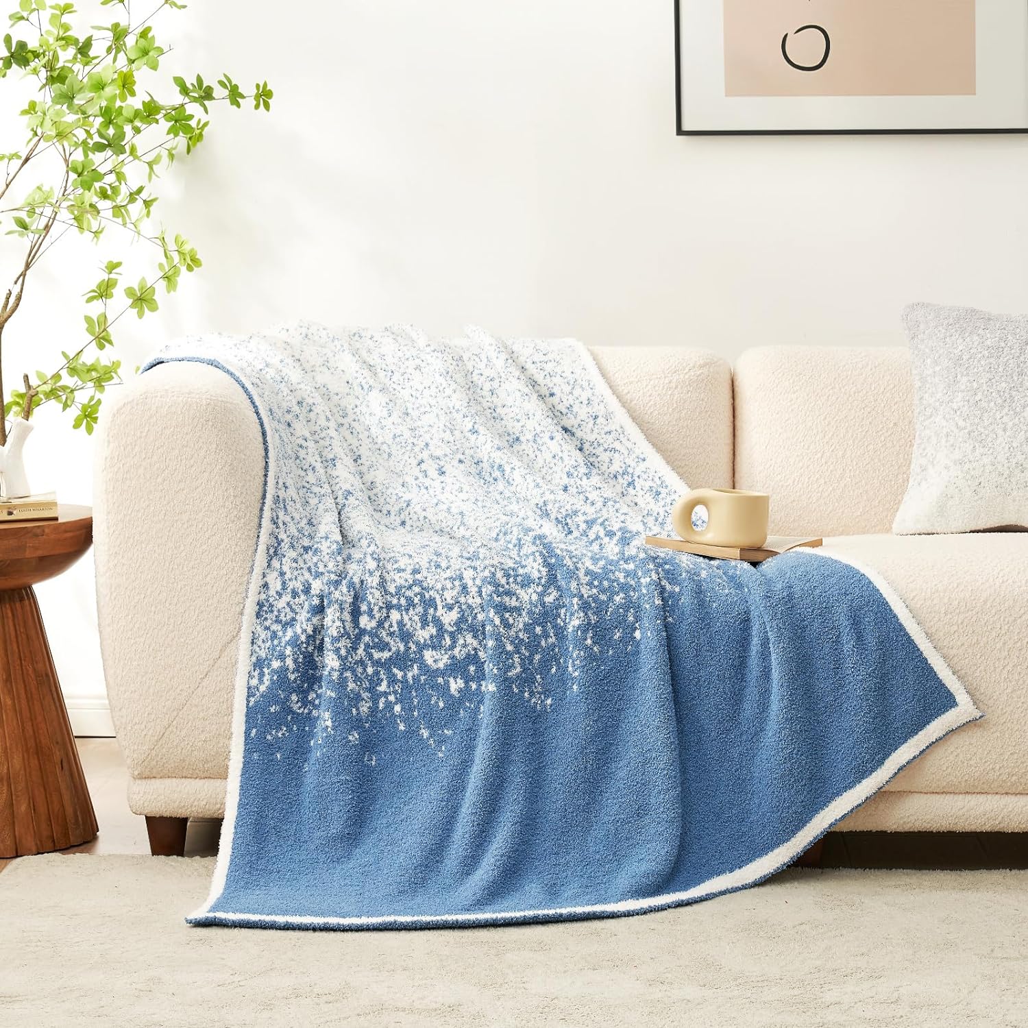 Snuggle Sacs Reversible Ombre Heather Feather Yarn Knit Throw Blanket on a beige couch with a book and mug #color_Blue