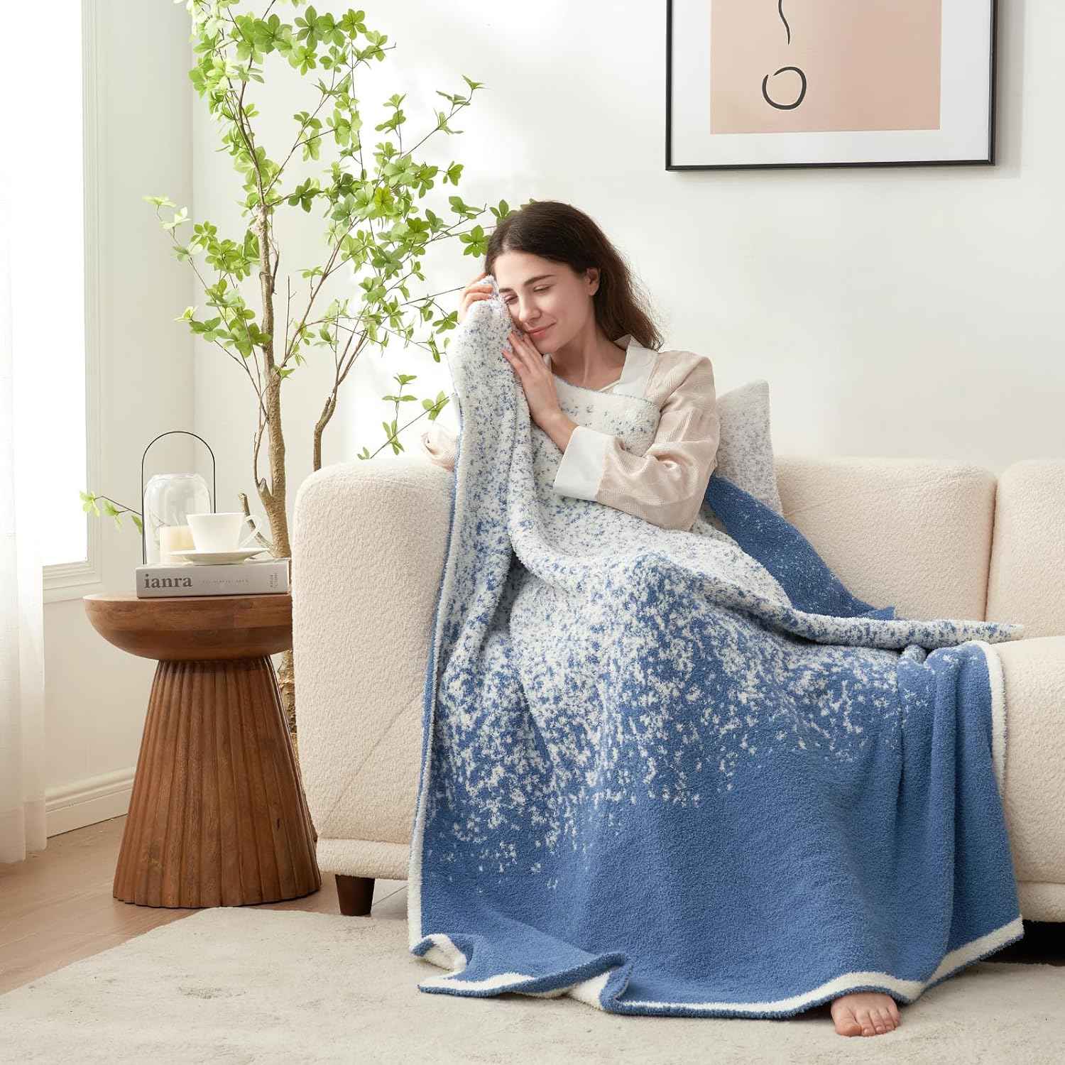 A woman sitting with Snuggle Sacs Reversible Ombre Heather Feather Yarn Knit Throw Blanket on a beige couch
#color_Blue