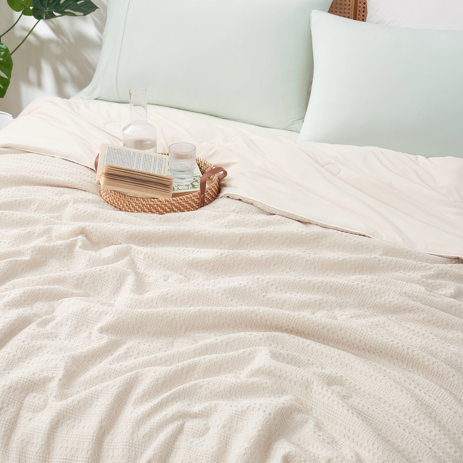Snuggle Sac Natural Fiber Waffle Cooling Comforter on a bed with pillows and cups on the bed#color_Beige
