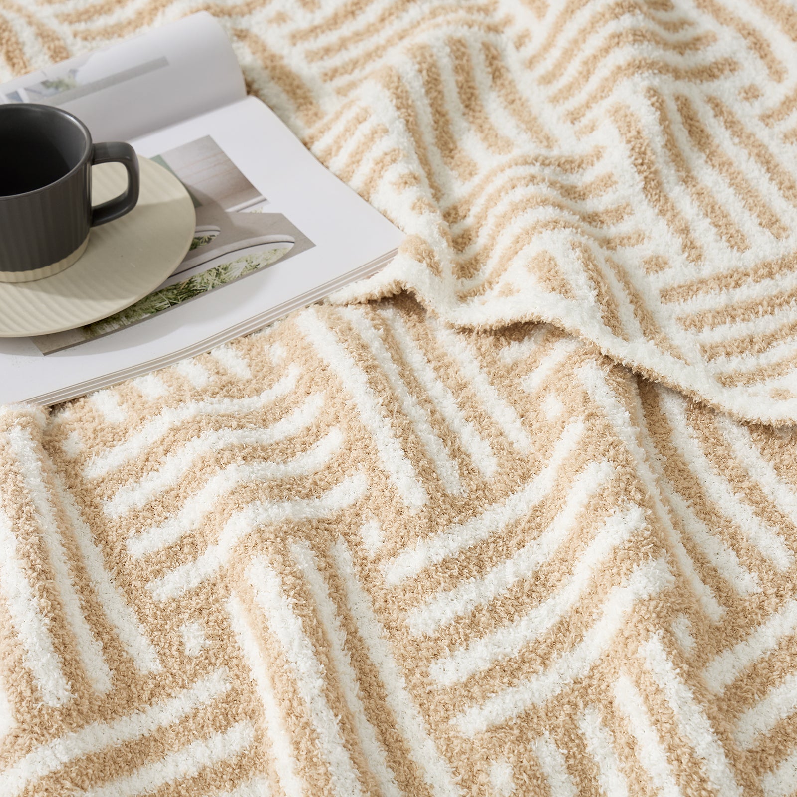 Close up of Classic Boho Feather Yarn Knit Throw Blanket with a mug and book #color_Beige