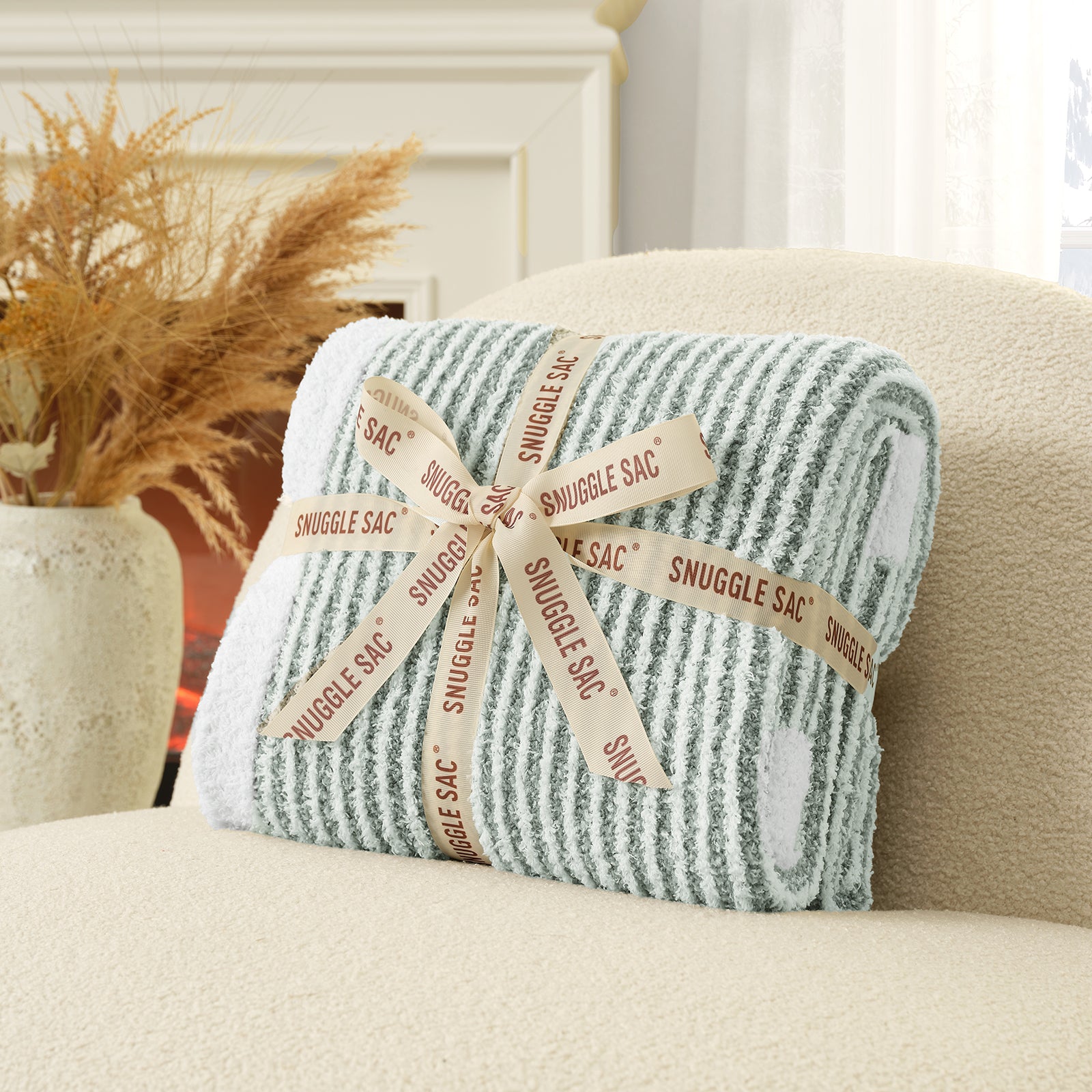 Folded blanket with 'Snuggle Sac' label on a couch #color_Green/Cream