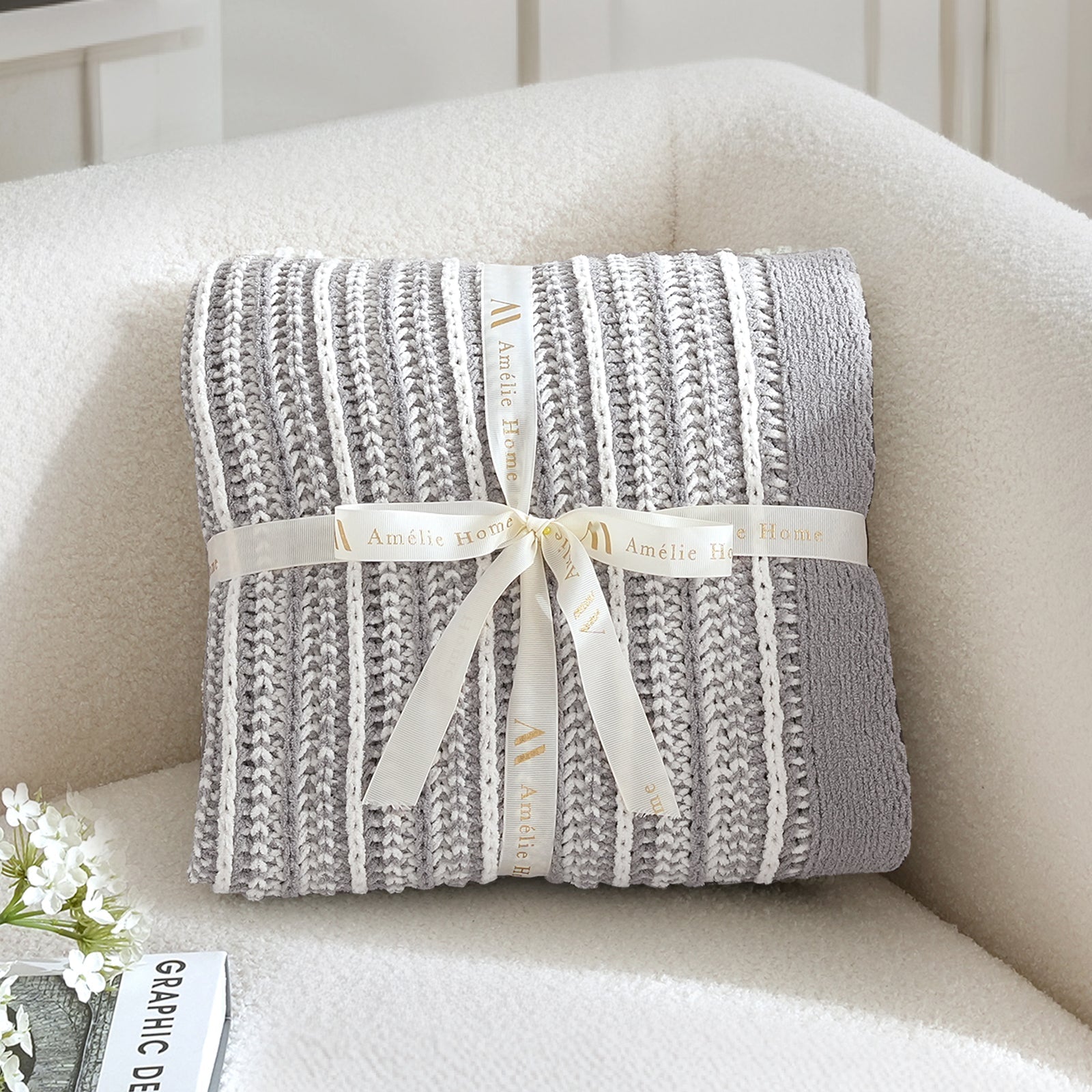 Gray knitted blanket with a white ribbon on a beige couch #color_Gray&White