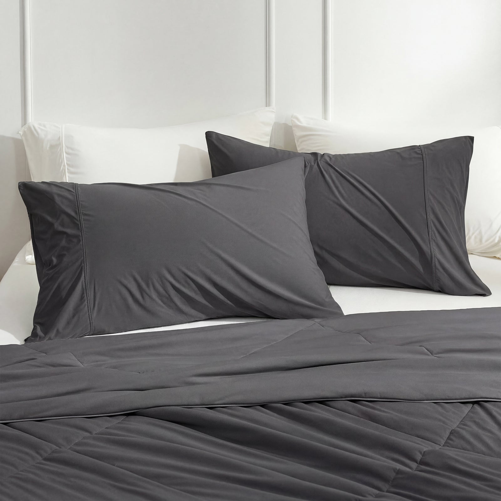 Gray bedding set on a bed with white pillows and headboard.#color_Charcoal Grey
