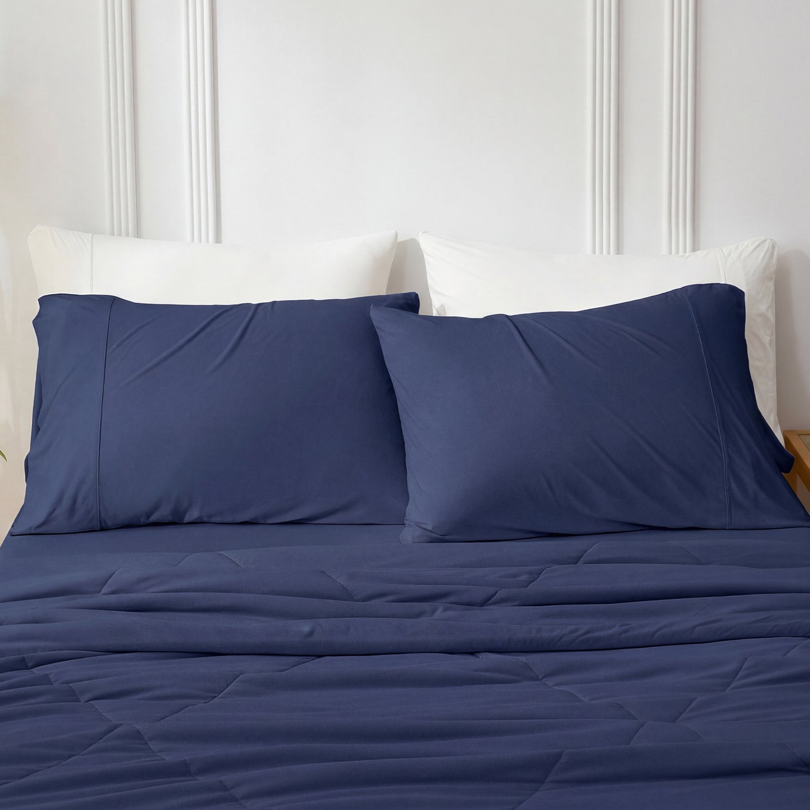 Dark blue bedding set on a bed with white pillows against a neutral wall.#color_Dark Blue