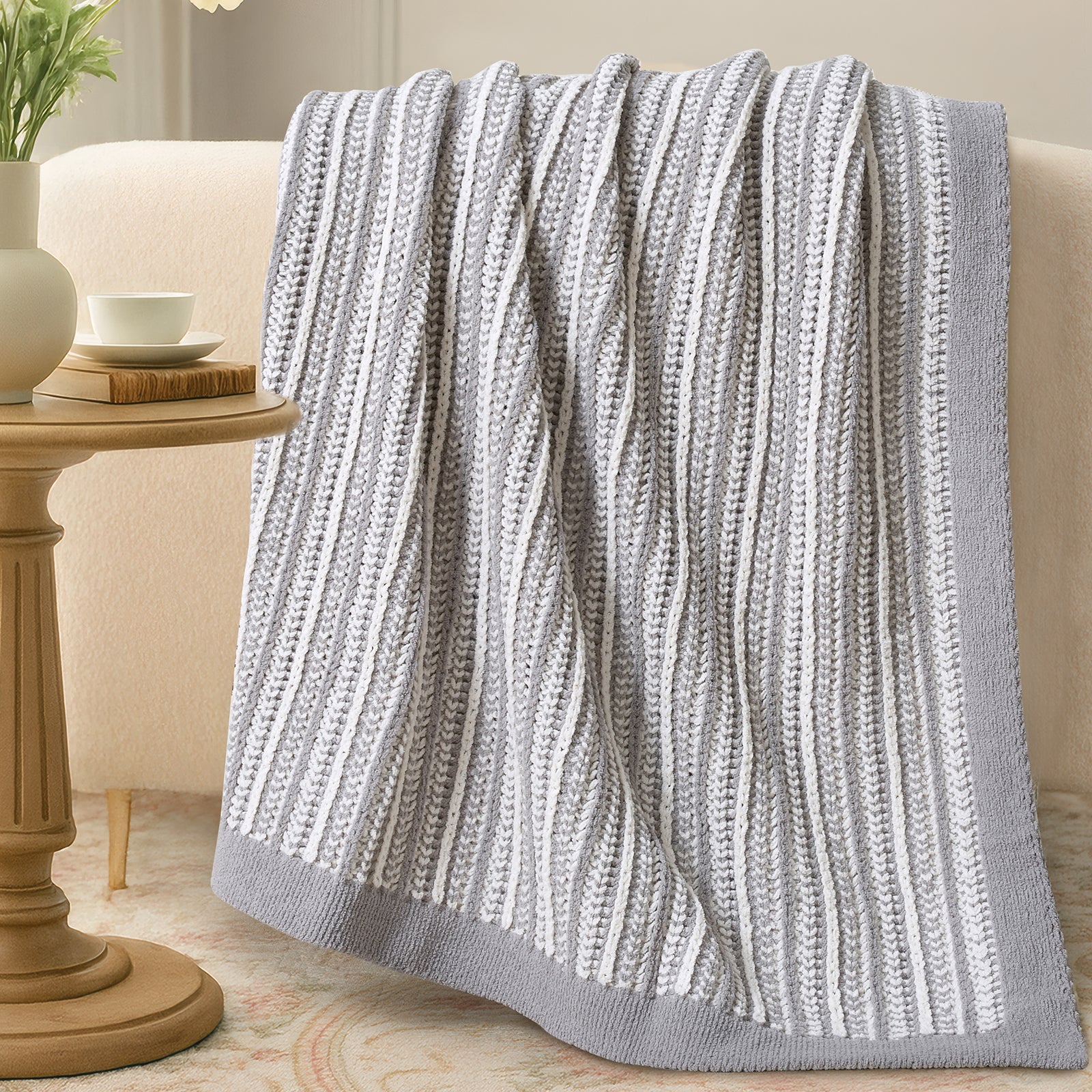 Knitted gray blanket draped over a sofa in a cozy living room setting. #color_Gray&White