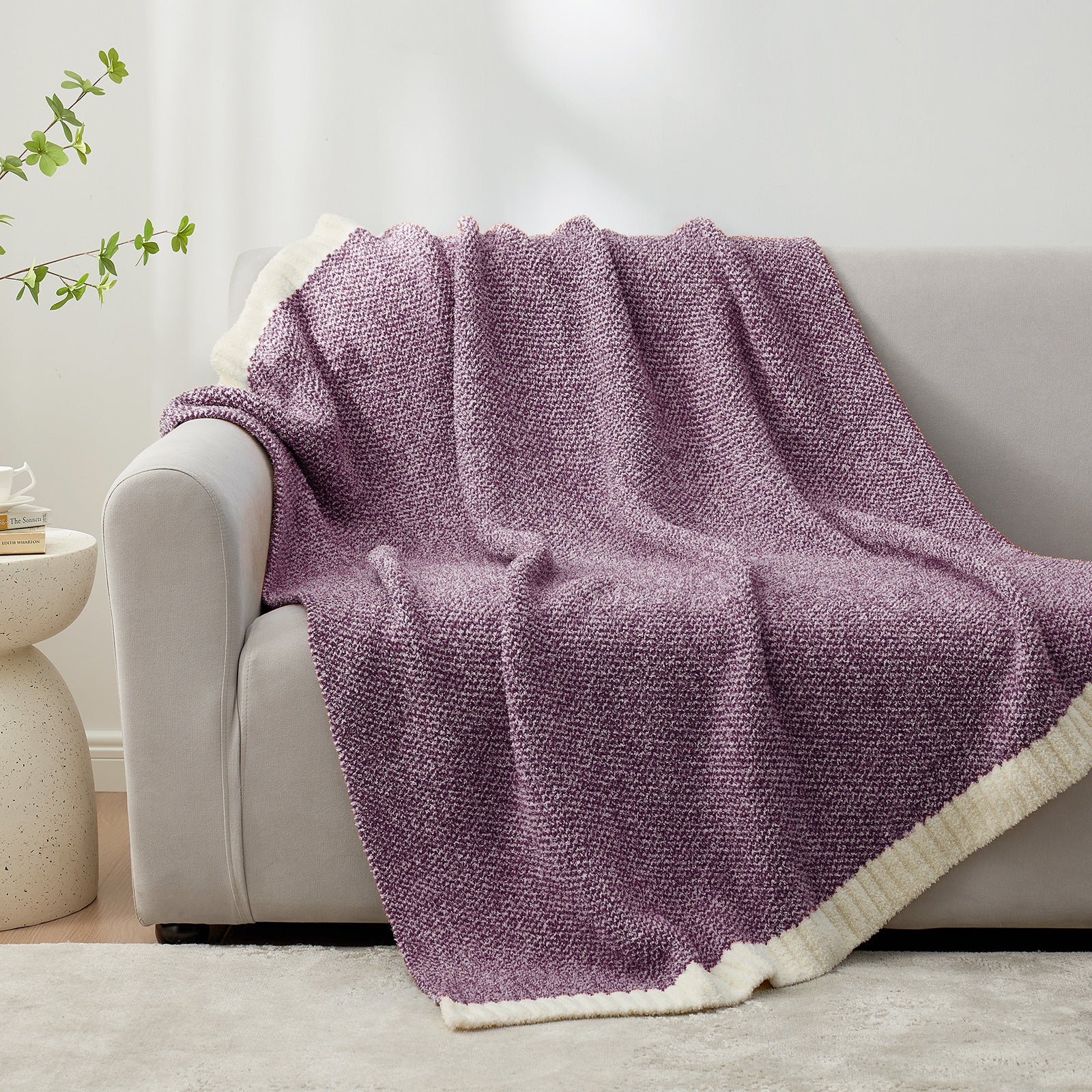 Purple textured blanket draped over a white armchair in a room with a plant and side table #color_Heather Purple
