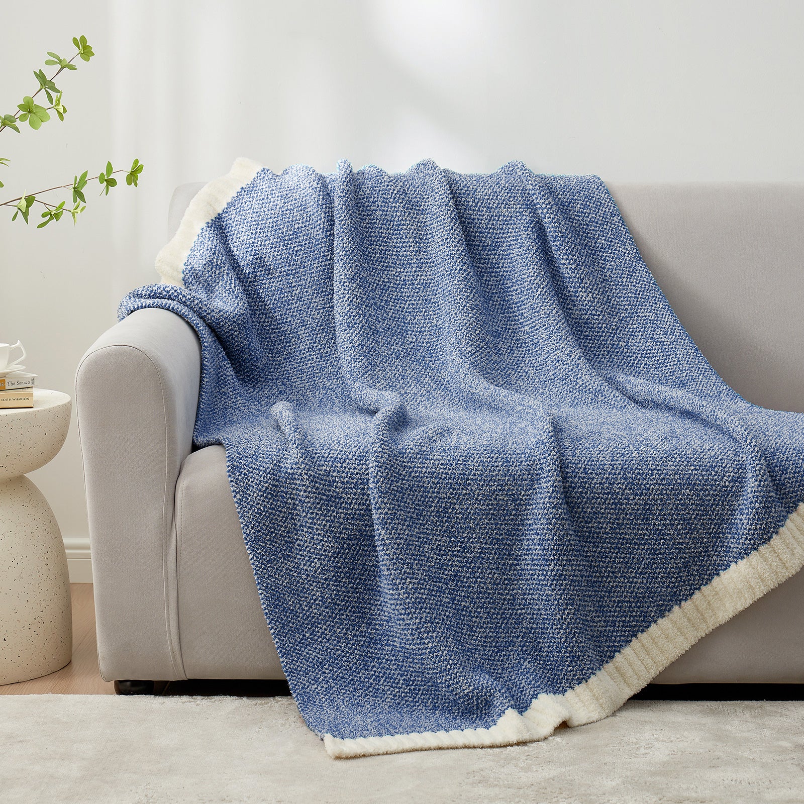 Blue textured blanket draped over a beige sofa in a living room setting. #color_Heather Royal Blue