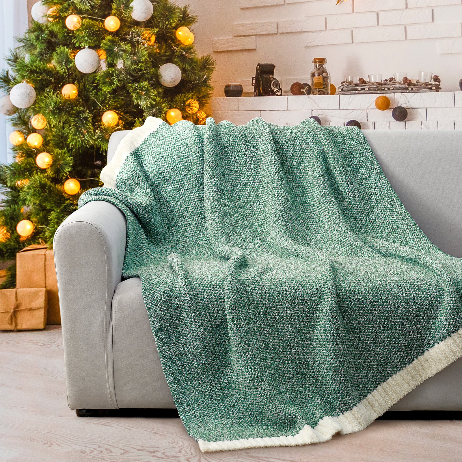 Green blanket draped over a sofa with a decorated Christmas tree in the background #Color_Heather Green