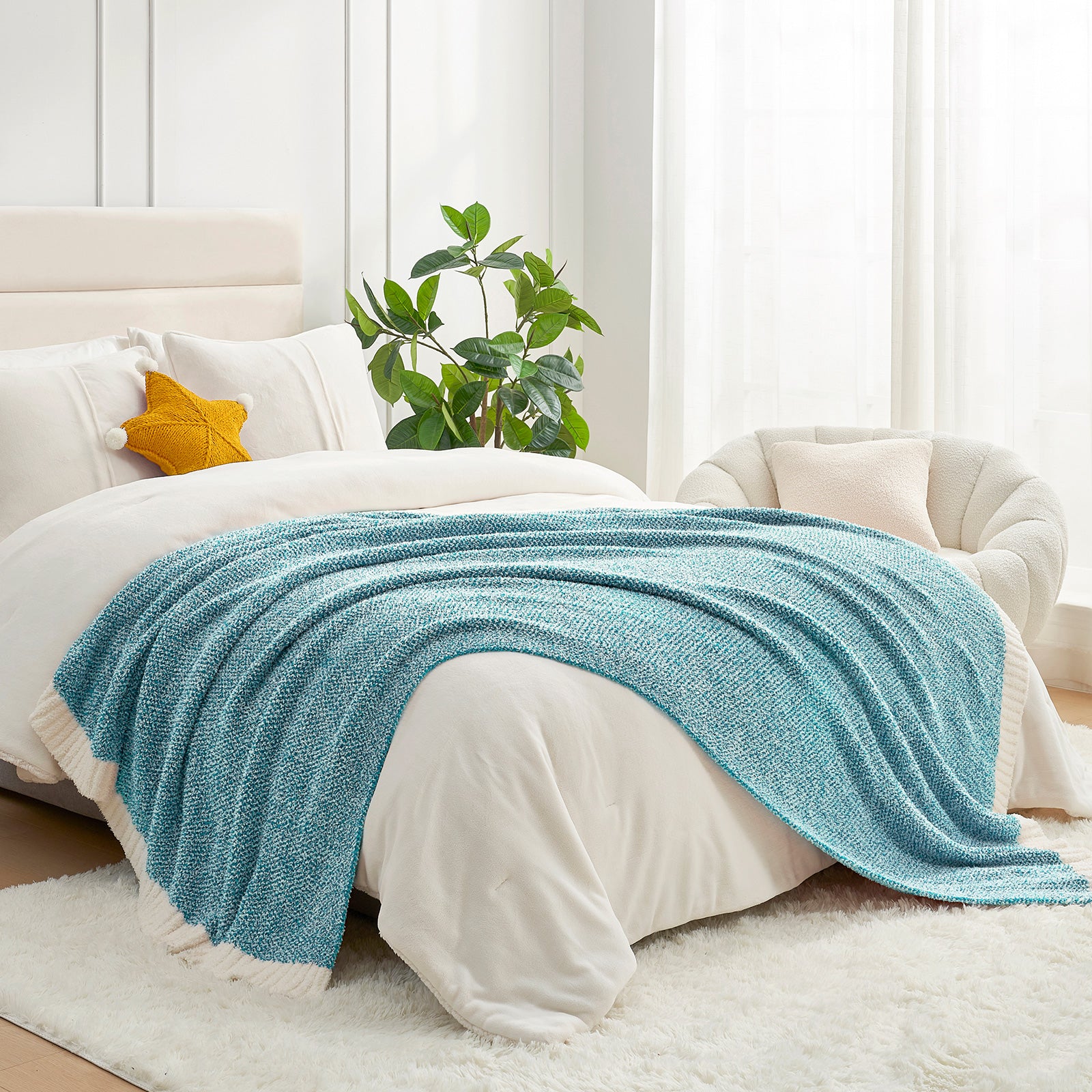 Blue blanket draped over a bed in a bright bedroom with a plant and window.  #color_Heather Teal