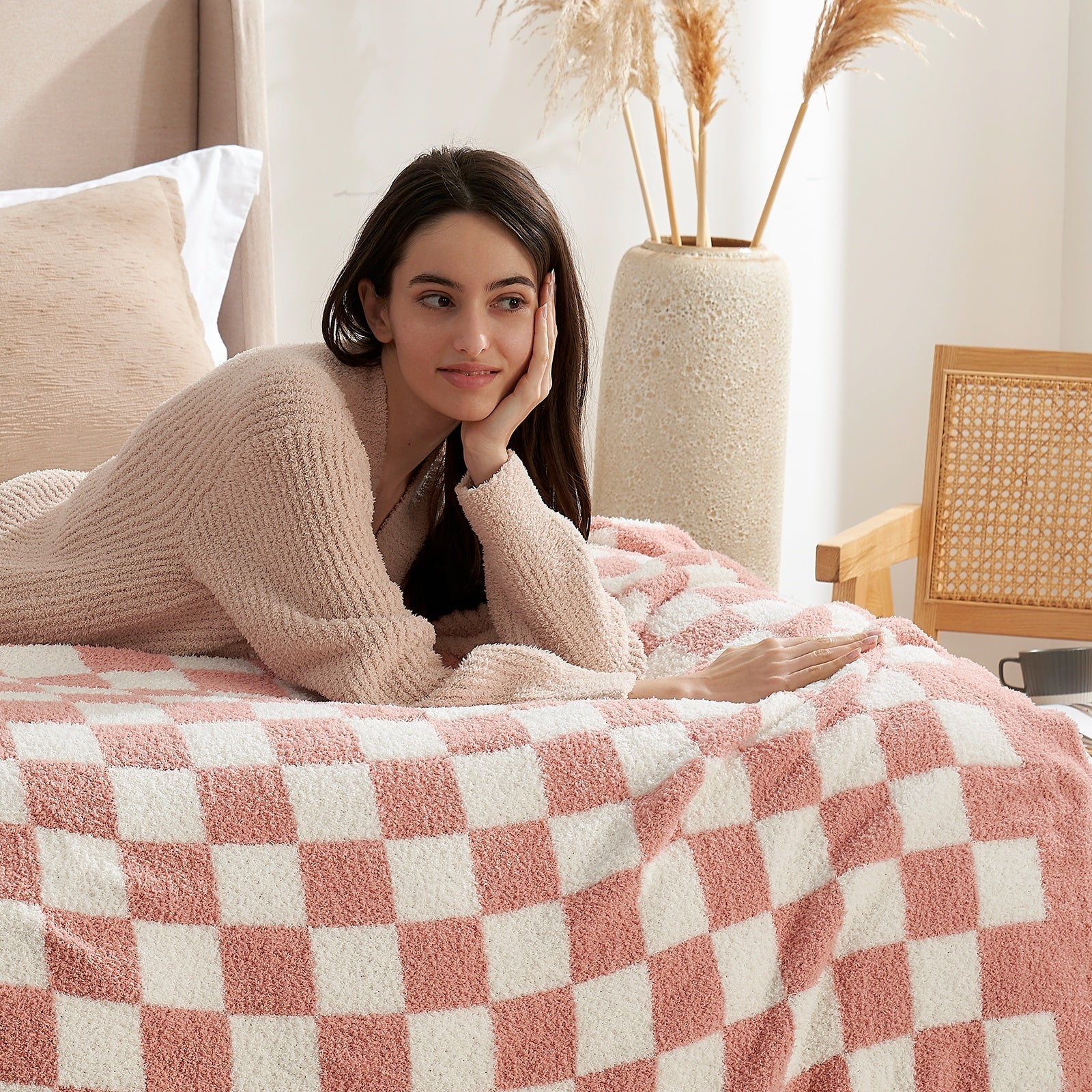 Woman lying on a bed with a pink and white checkered blanket, surrounded by decorative elements.#color_Checkered Pink