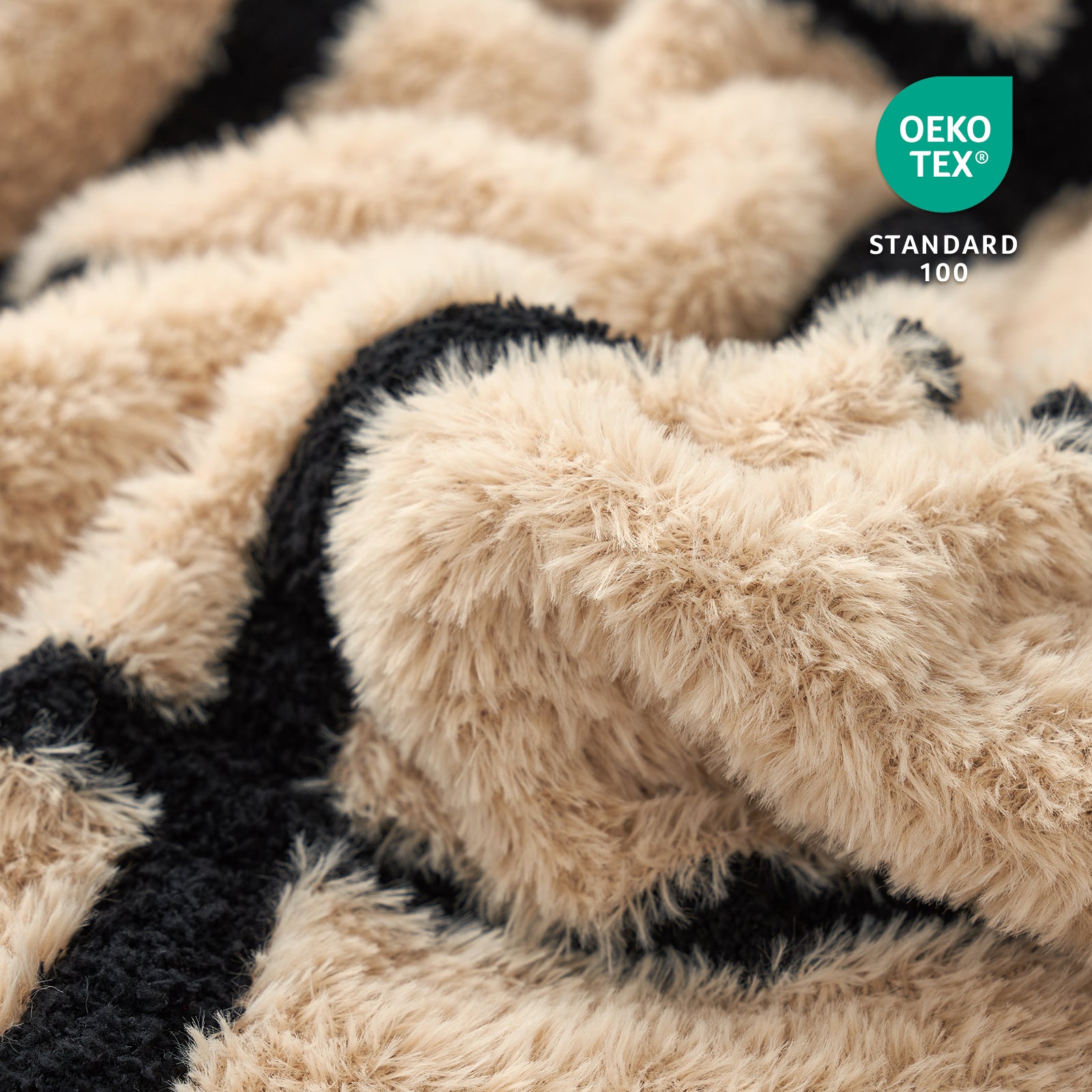 Close-up of a textured beige and black fabric blanket with Oeko-Tex Standard 100 logo.#color_Black