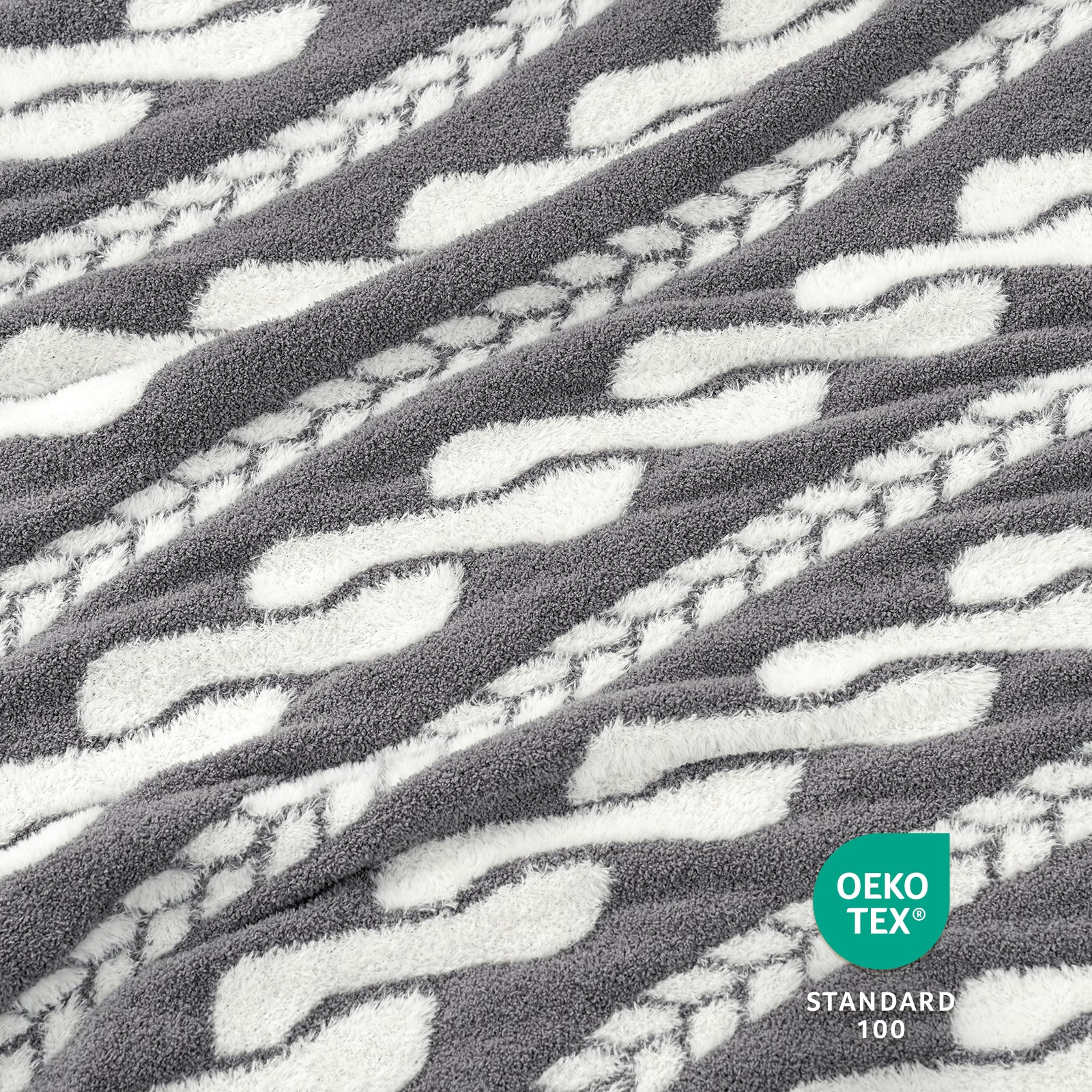 Close-up of Snuggle Sac gray and white Cable pattern Faux Fur Knit Throw Blanket textured fabric with OEKO-TEX logo.#color_Gray