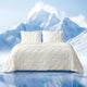 Snuggle Sac Cooling comforter in white on bed in a bedroom with mountains in snow as a view behind#color_White