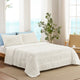 Snuggle Sac Cooling comforter in white on bed in a bedroom with windows,plant and a view behind#color_White