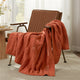 Snuggle Sac cable chenille knit throw blanket in Burnt Orange draped over a chair creating a cozy corner #color_Burnt Orange