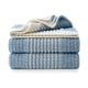 Stack of Snuggle Sac blue and white textured blankets on a white background #color_Ombre Blue