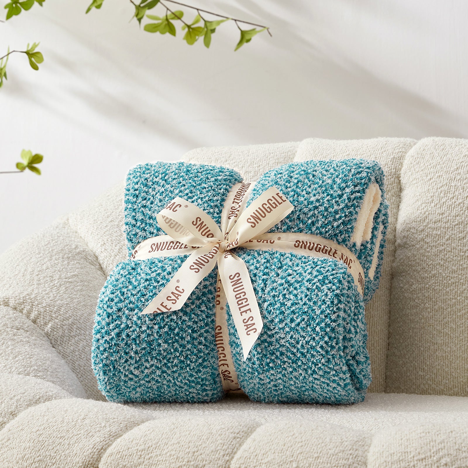 Turquoise blanket with 'Snuggie' label on a beige couch  #color_Heather Teal