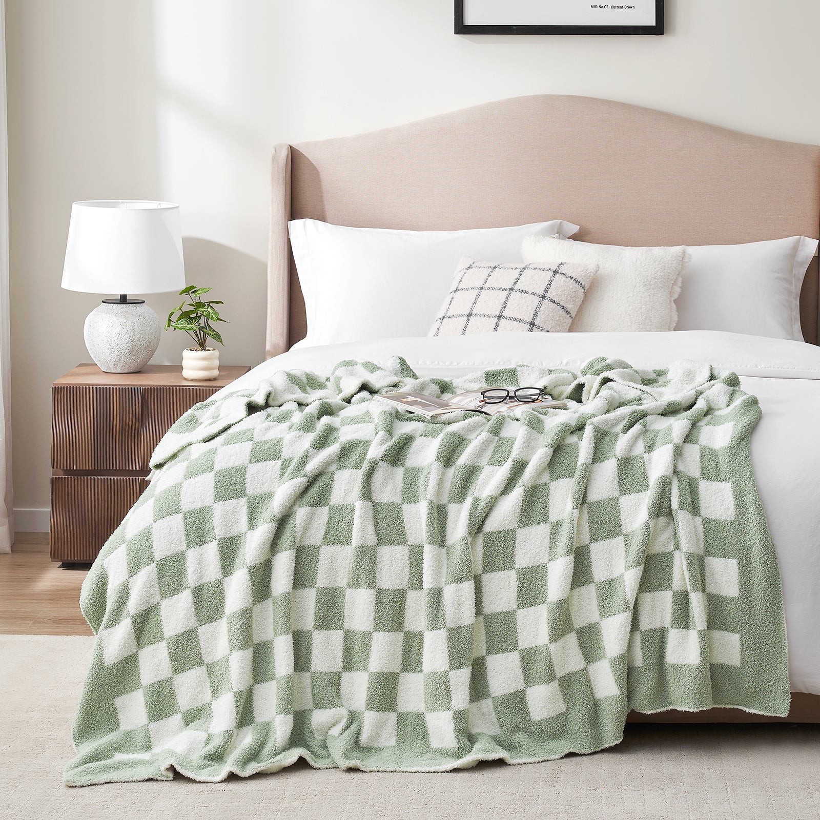 Bed with a checkered green and white blanket, pillows, and a lamp on a nightstand. #color_Checkered Sage Green