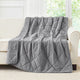 Snuggle Sac Dark Grey cooling blanket draped over a beige sofa in a room with large windows.#color_Dark Grey