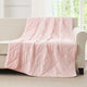 Snuggle Sac Pink cooling blanket draped over a beige sofa in a room with large windows.#color_Pink