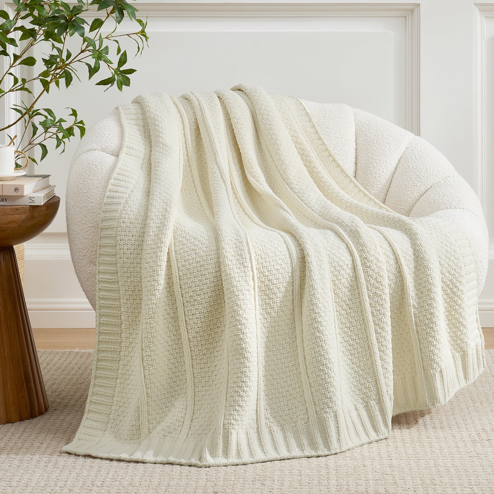 Ivory textured blanket draped over a chair in a room with a plant and table. #color_Ivory
