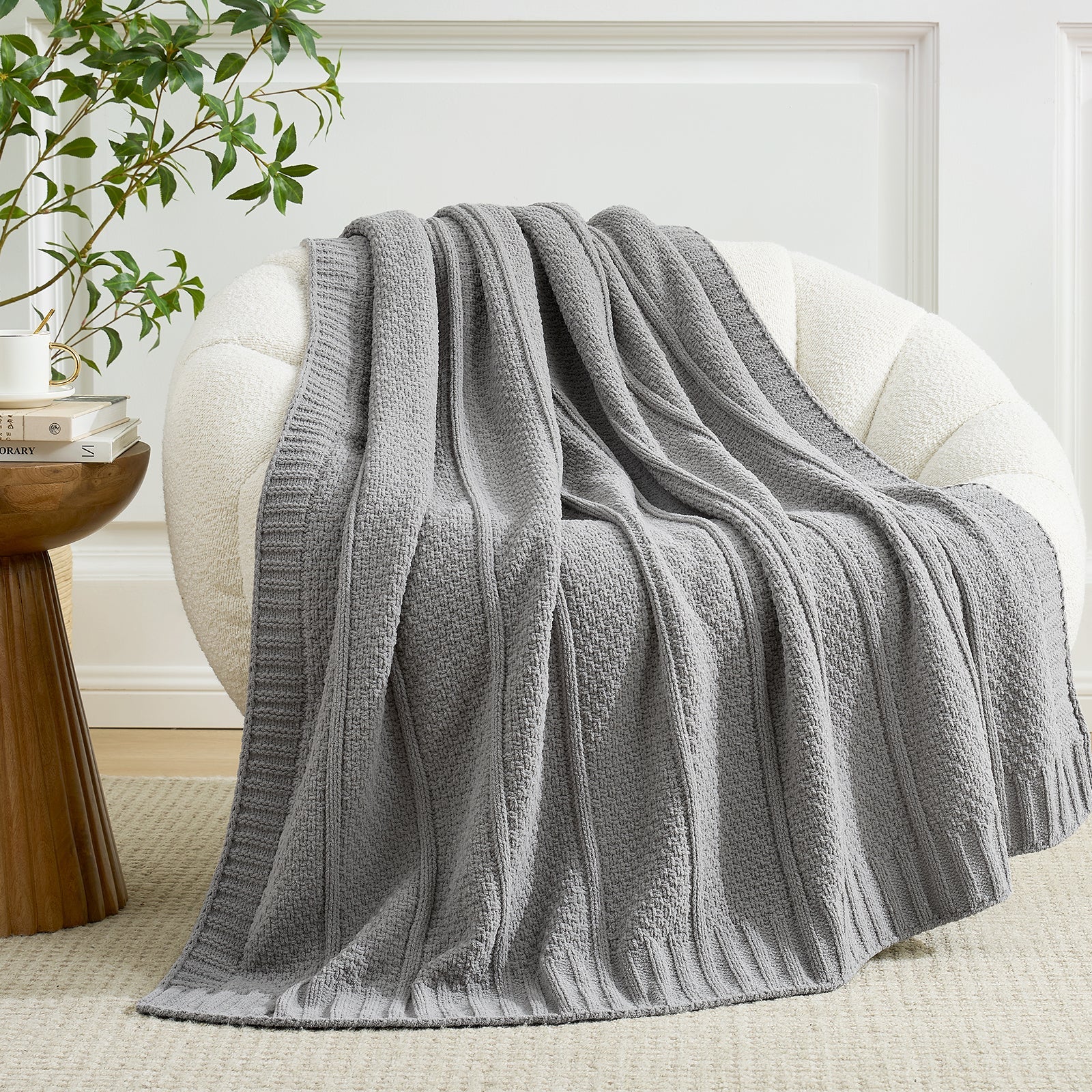 Snuggle Sac gray textured blanket draped over a white armchair in a cozy living room setting. #color_Gray