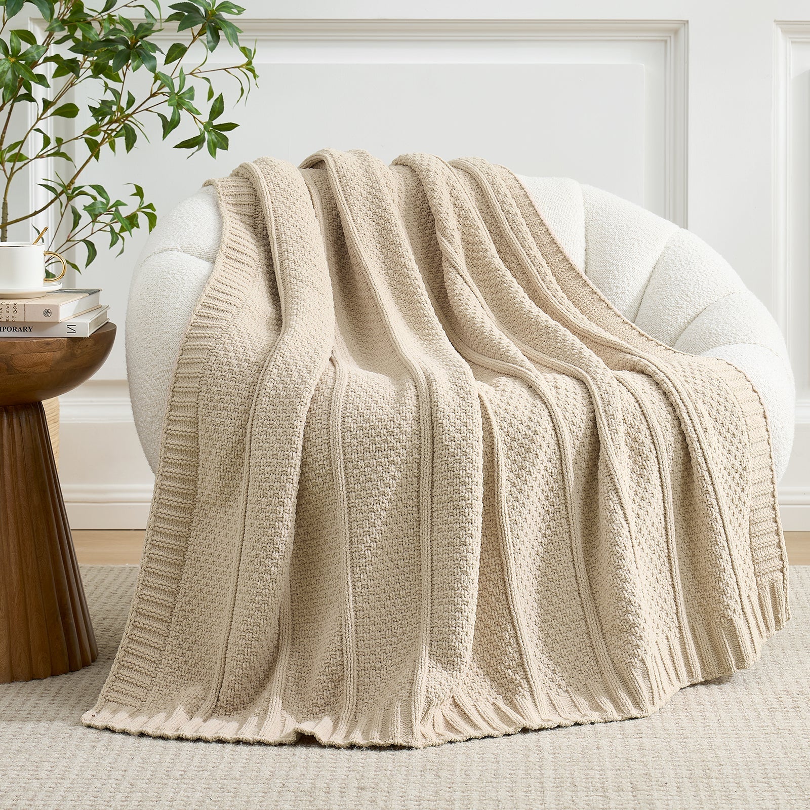 Beige knitted blanket draped over a chair in a cozy living room setting. #color_Beige
