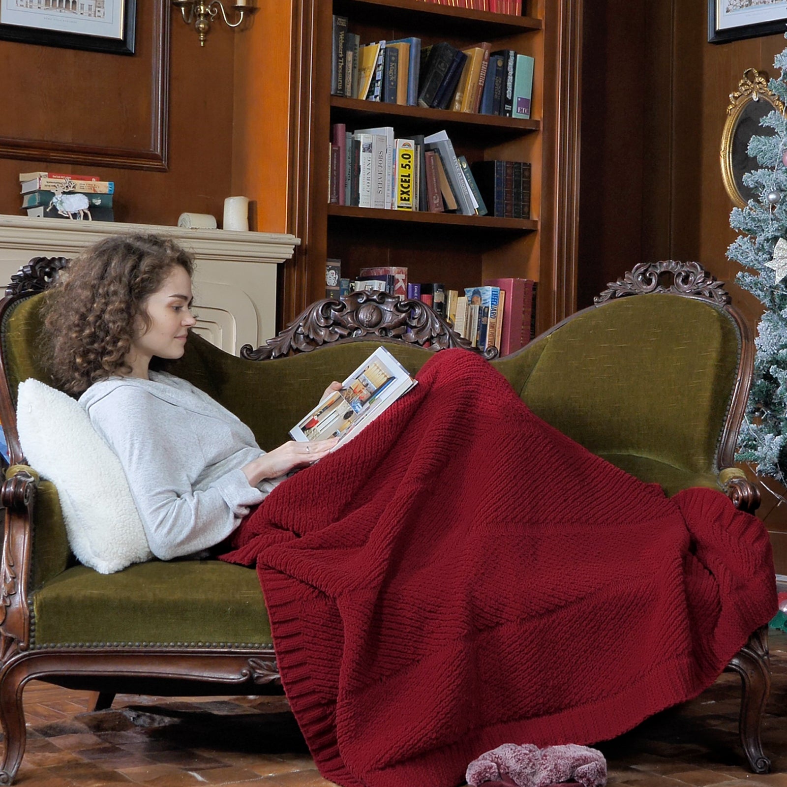 Woman relaxing on sofa with a Snuggle Sac chevron chenille knit throw blanket in Red while reading #color_Red