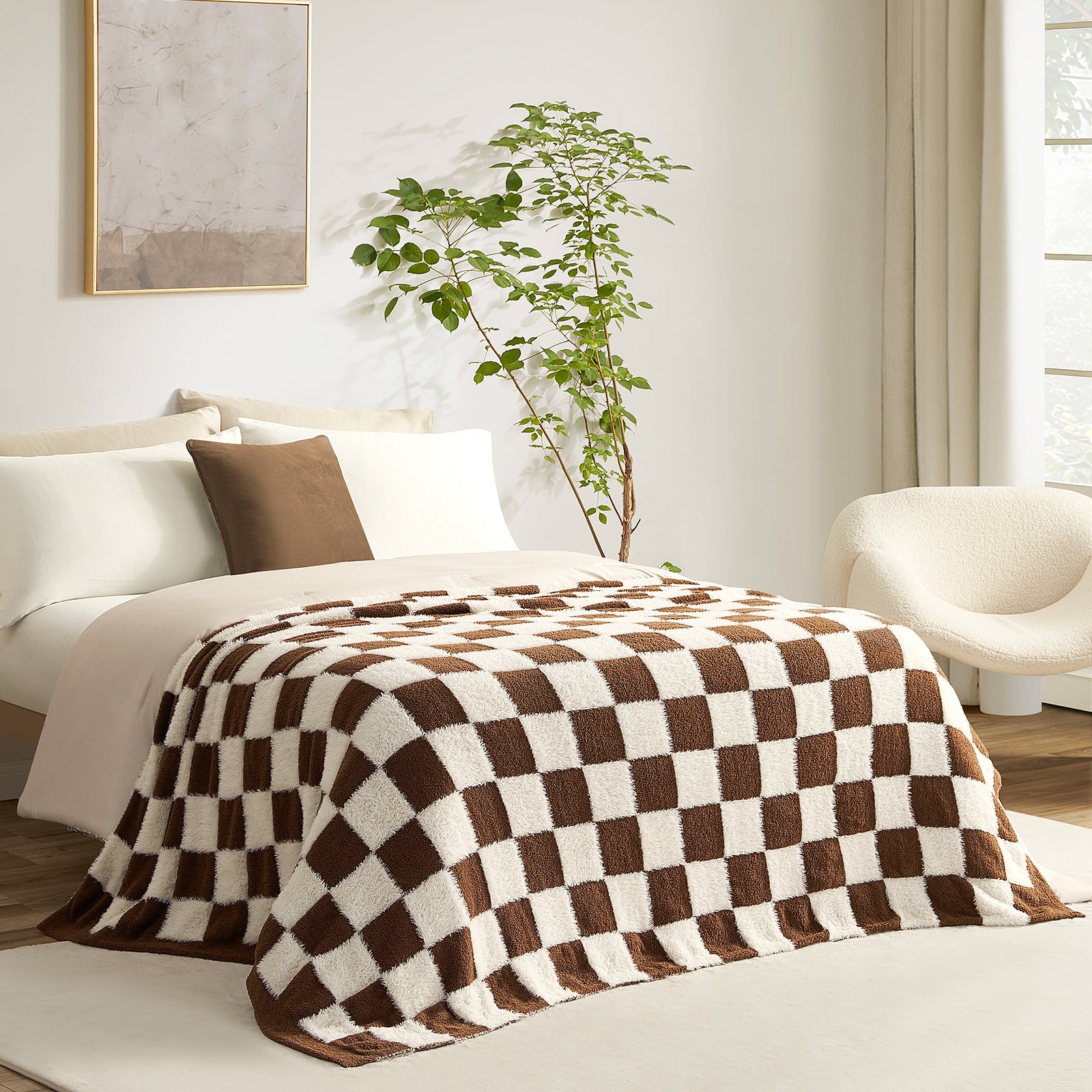 Checkered brown and white blanket on a bed in a bright bedroom with a plant and chair.#color_Brown