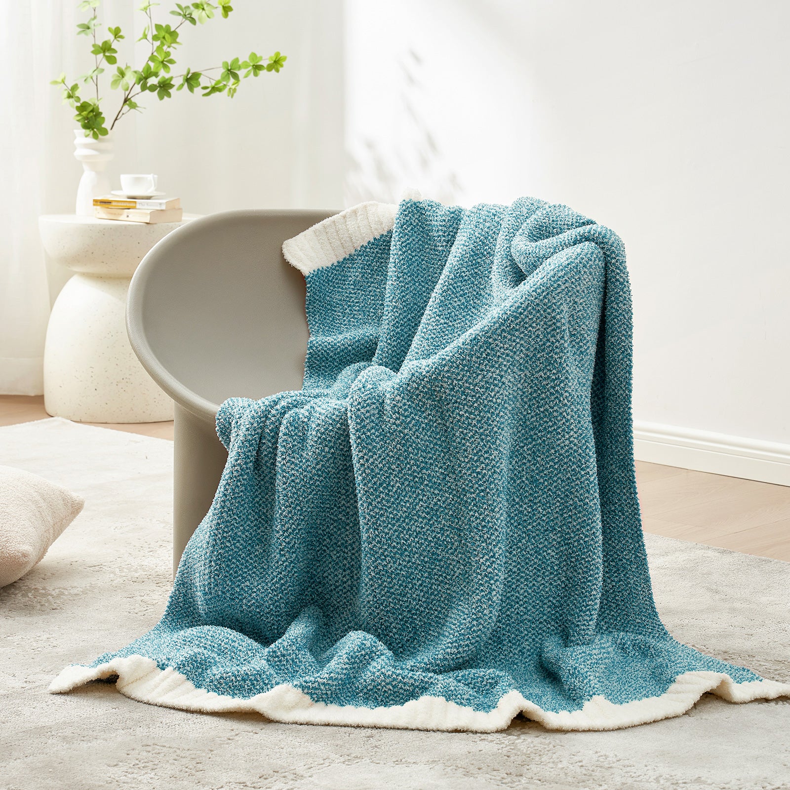Blue textured blanket draped over a chair in a cozy living room setting.  #color_Heather Teal