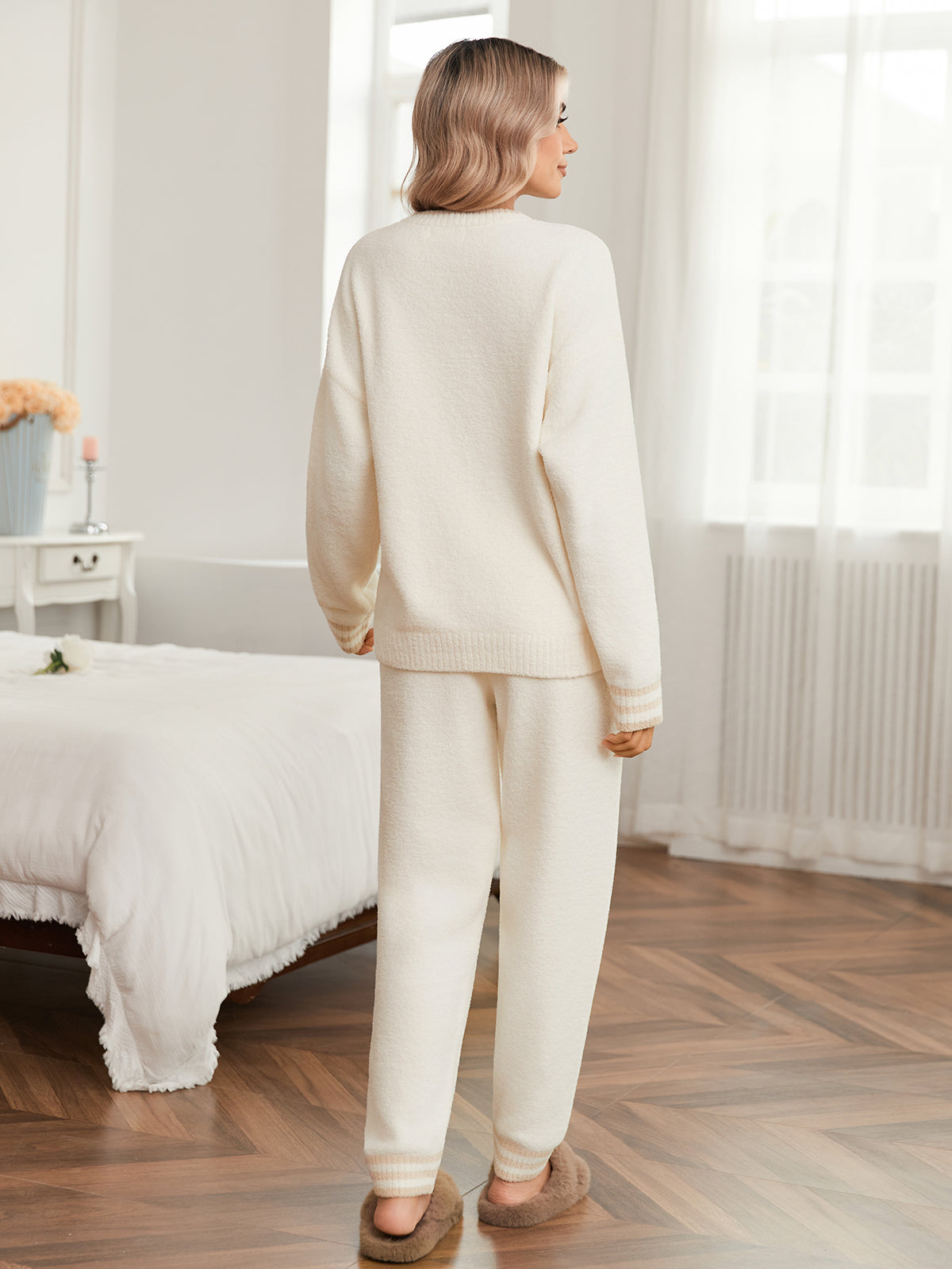 Woman in a cream-colored outfit standing in a bedroom. #color_Ivory