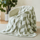 Snuggle Sacs Chevron Feather Yarn Knit Throw Blanket on the chair with lamp and window behind#color_Sage Green