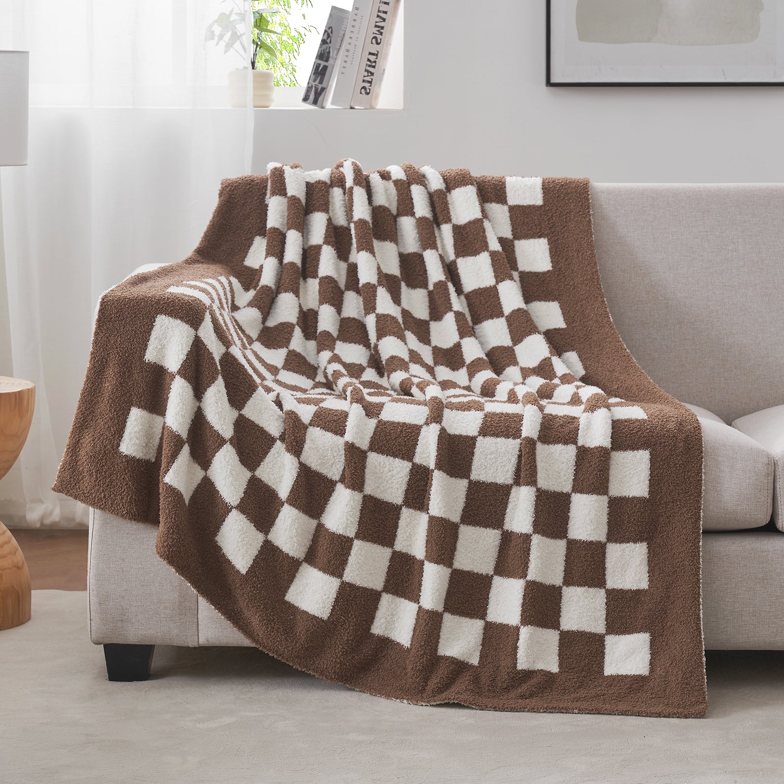 Checkered brown and white blanket draped over a sofa in a living room setting. #color_Checkered Brown