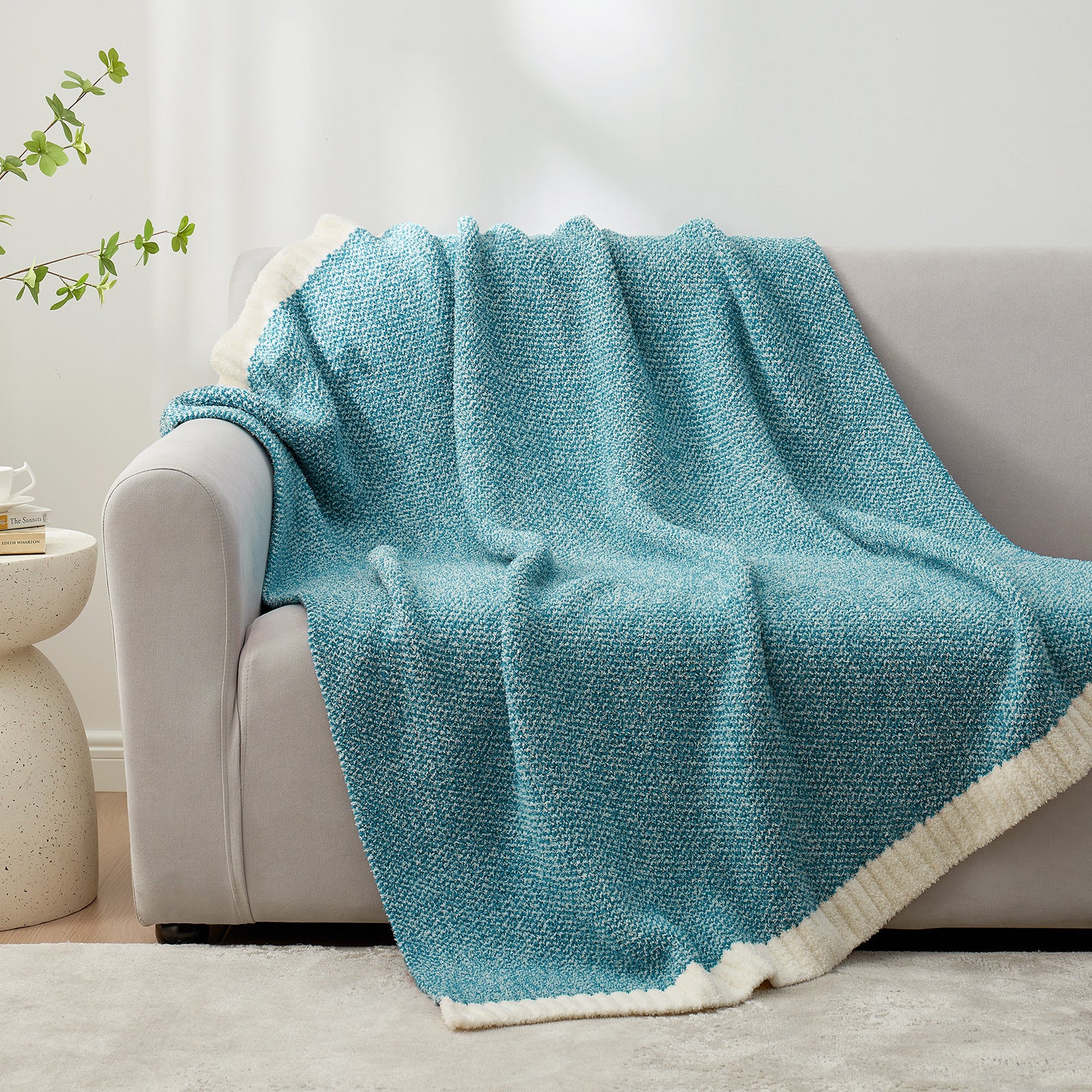 Turquoise blanket draped over a gray sofa in a living room setting.  #color_Heather Teal