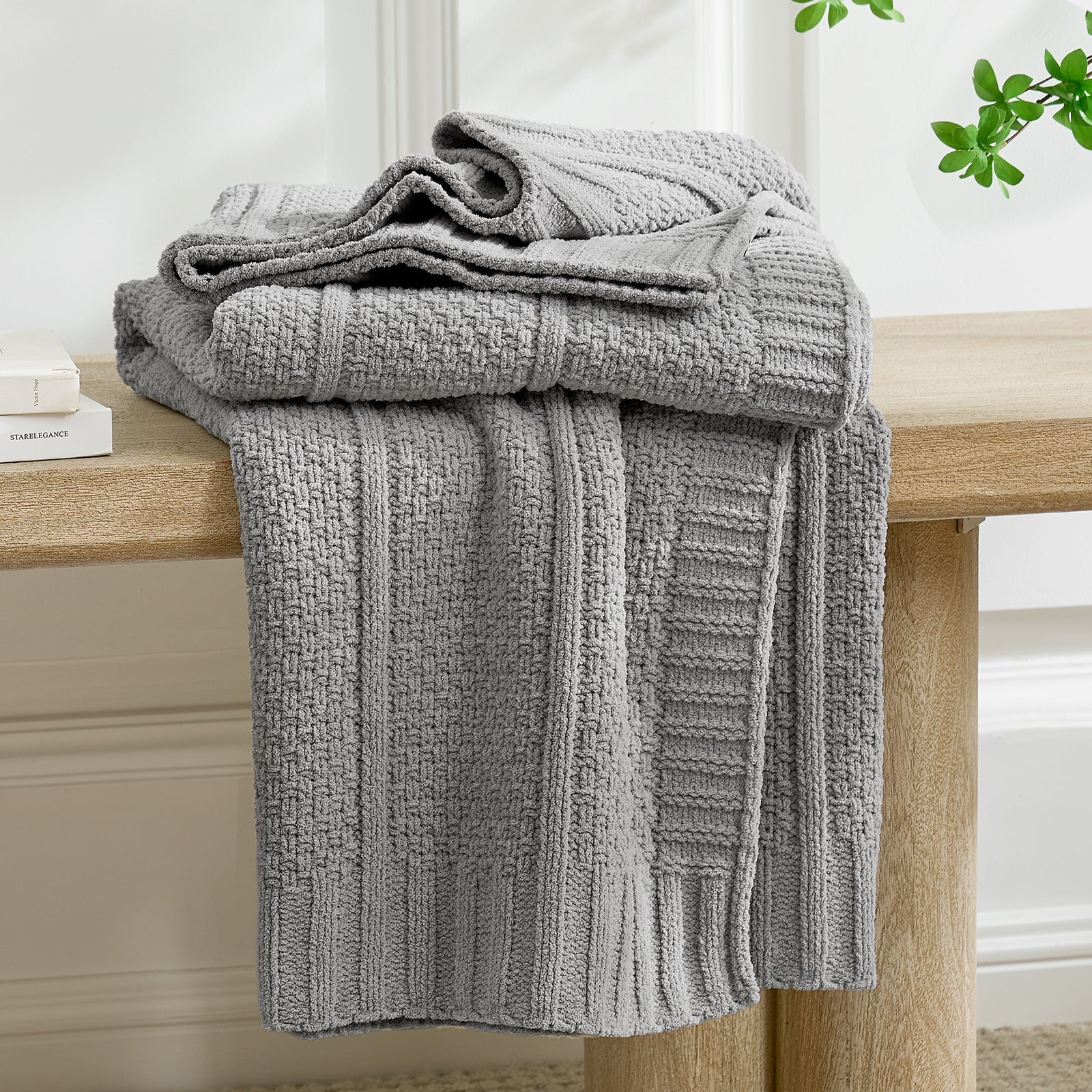Gray textured blanket draped over a wooden surface with a neutral background #color_Gray