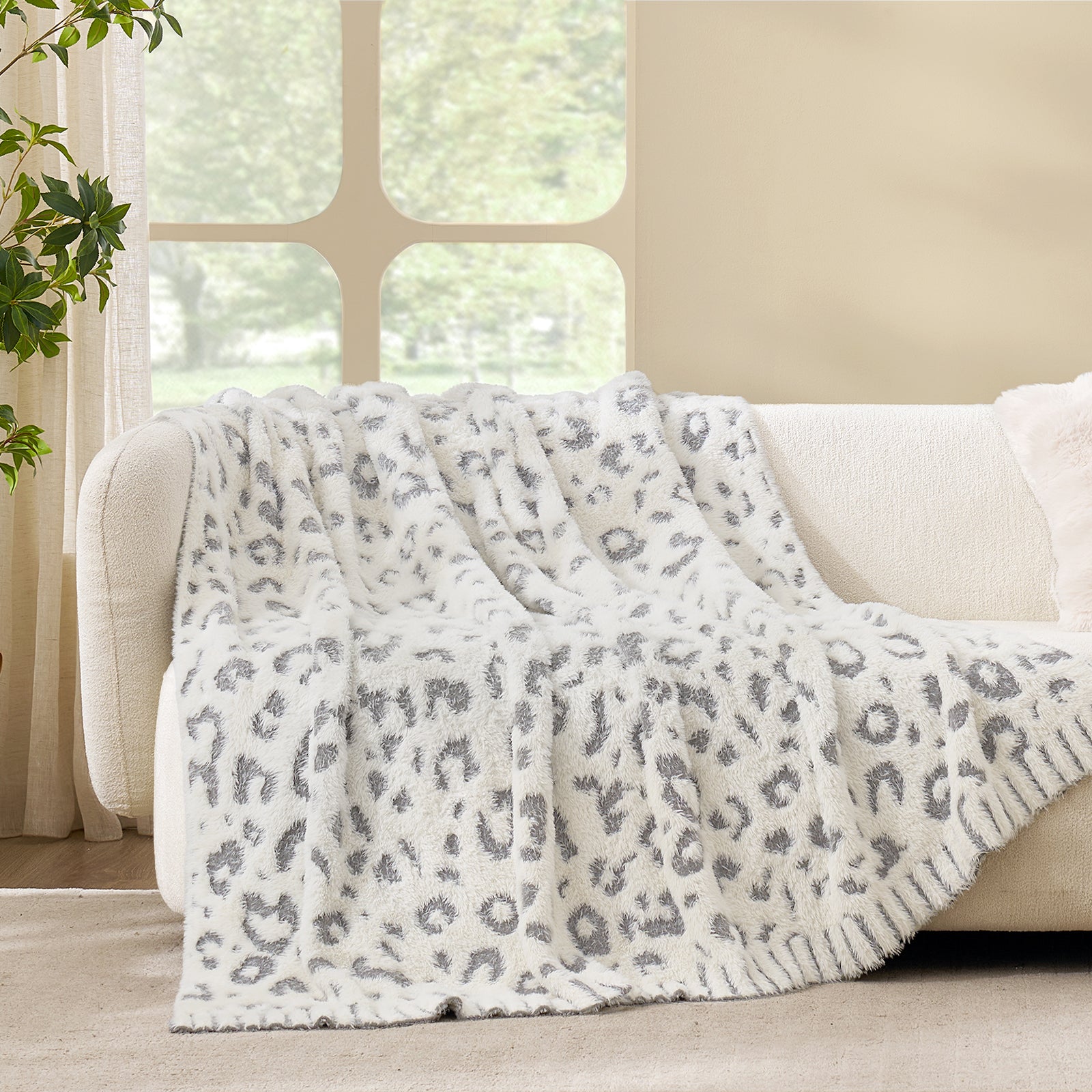 Leopard faux fur knit throw blanket in Grey Leopard draped over a sofa, showcasing soft texture and #color_Grey Leopard