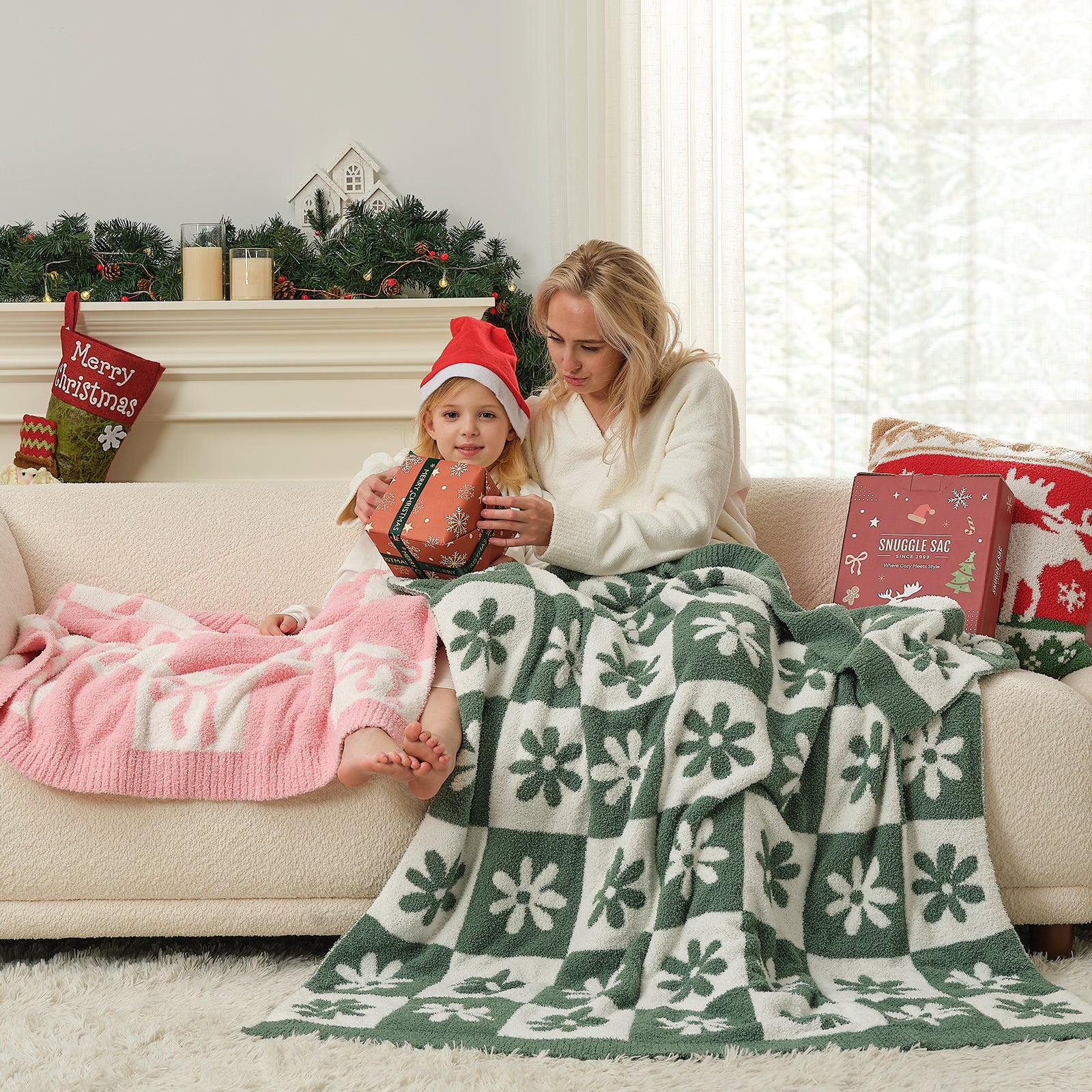 Woman and child sitting on a couch with a green and white patterned blanket, surrounded by Christmas decor. #color_Xmas Green