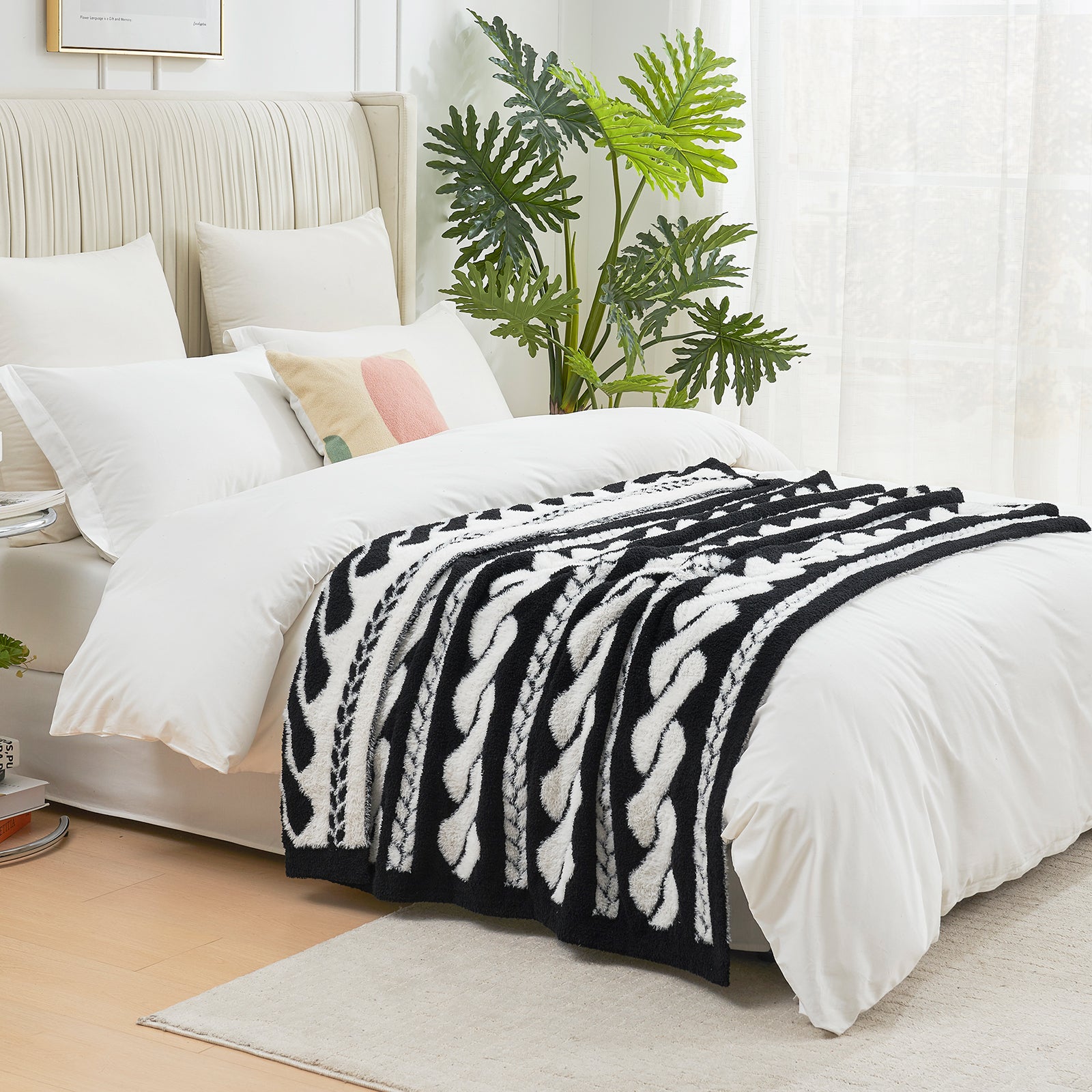 Cable pattern Faux Fur Knit Throw Blanket in black and white on a bed side view.#color_Black