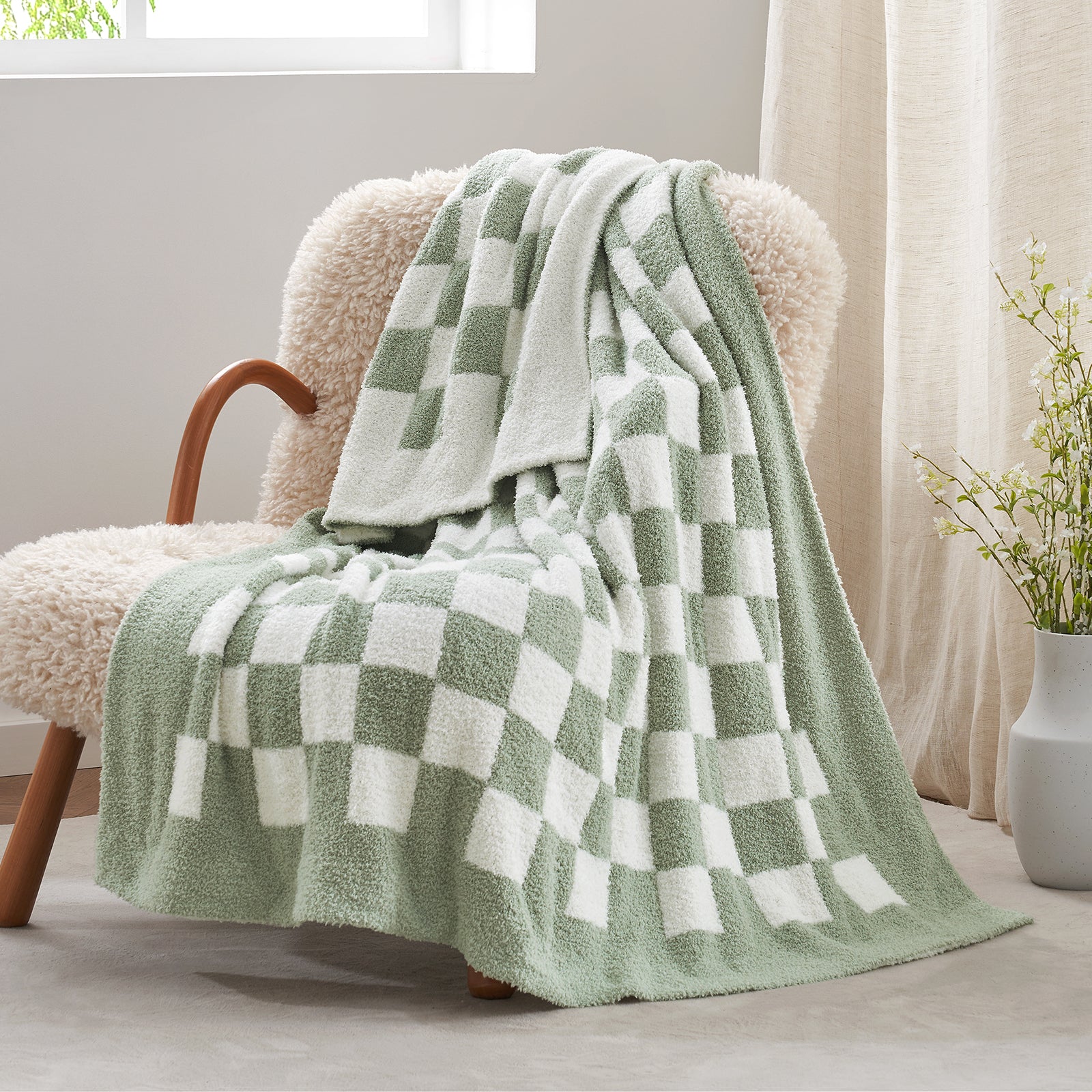 Green and white checkered blanket draped over a beige armchair in a bright room. #color_Checkered Sage Green