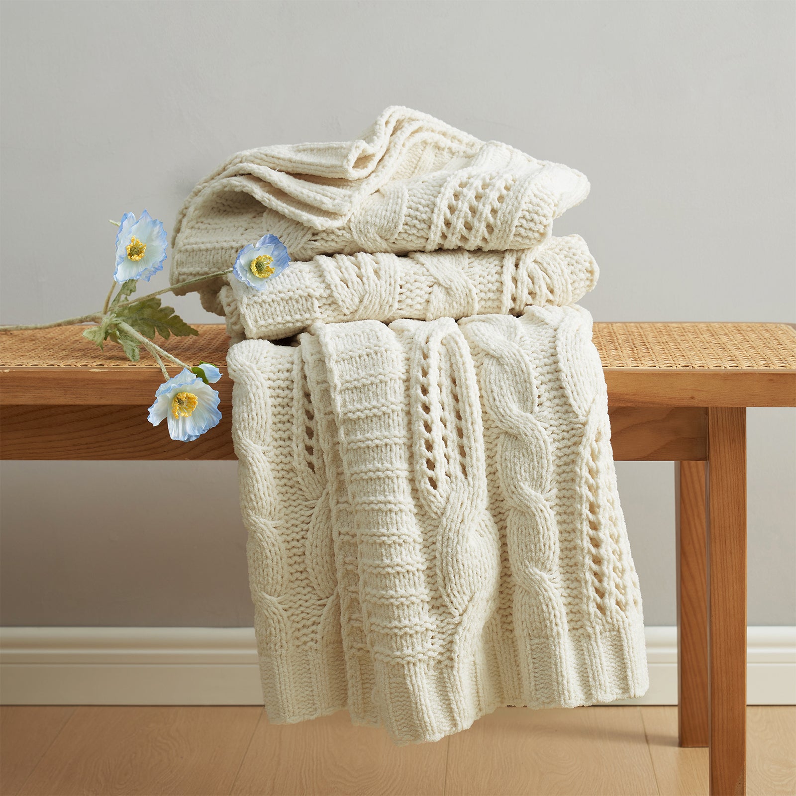 Cable chenille knit throw blanket in Ivory neatly folded on a wooden table showcasing cable texture #color_Ivory