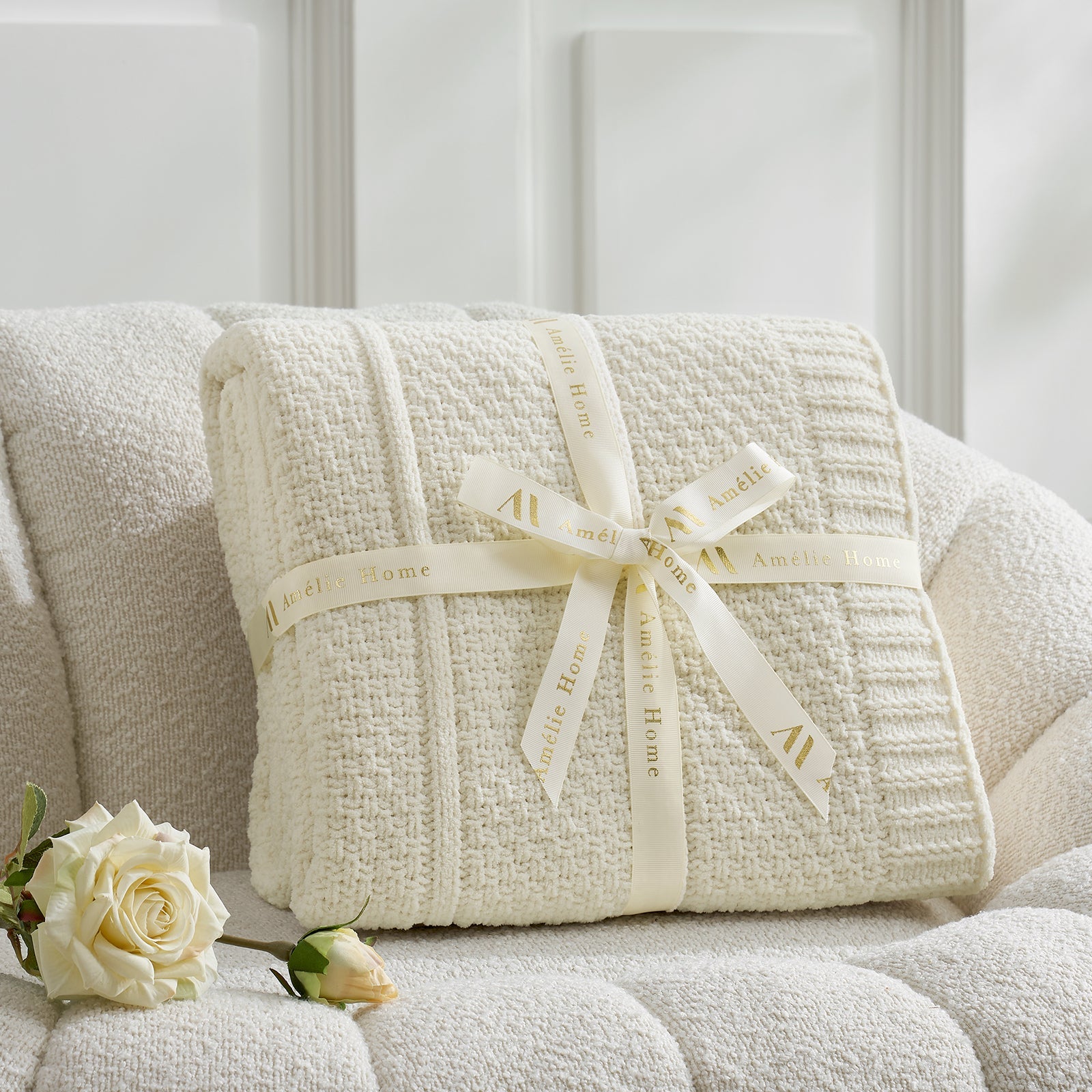 Ivory textured blanket with a ribbon on a white couch, accompanied by a white rose. #color_Ivory