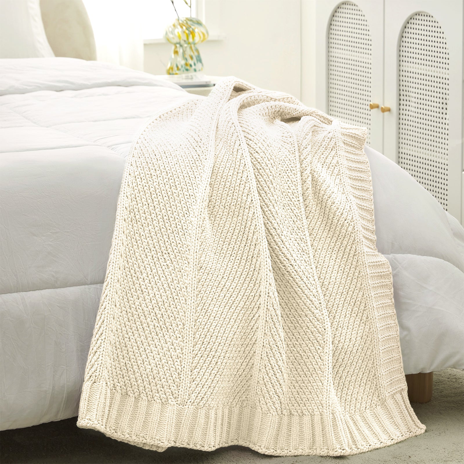 Chevron chenille knit throw blanket in Ivory placed at the foot of a bed adding texture and warmth #color_Ivory